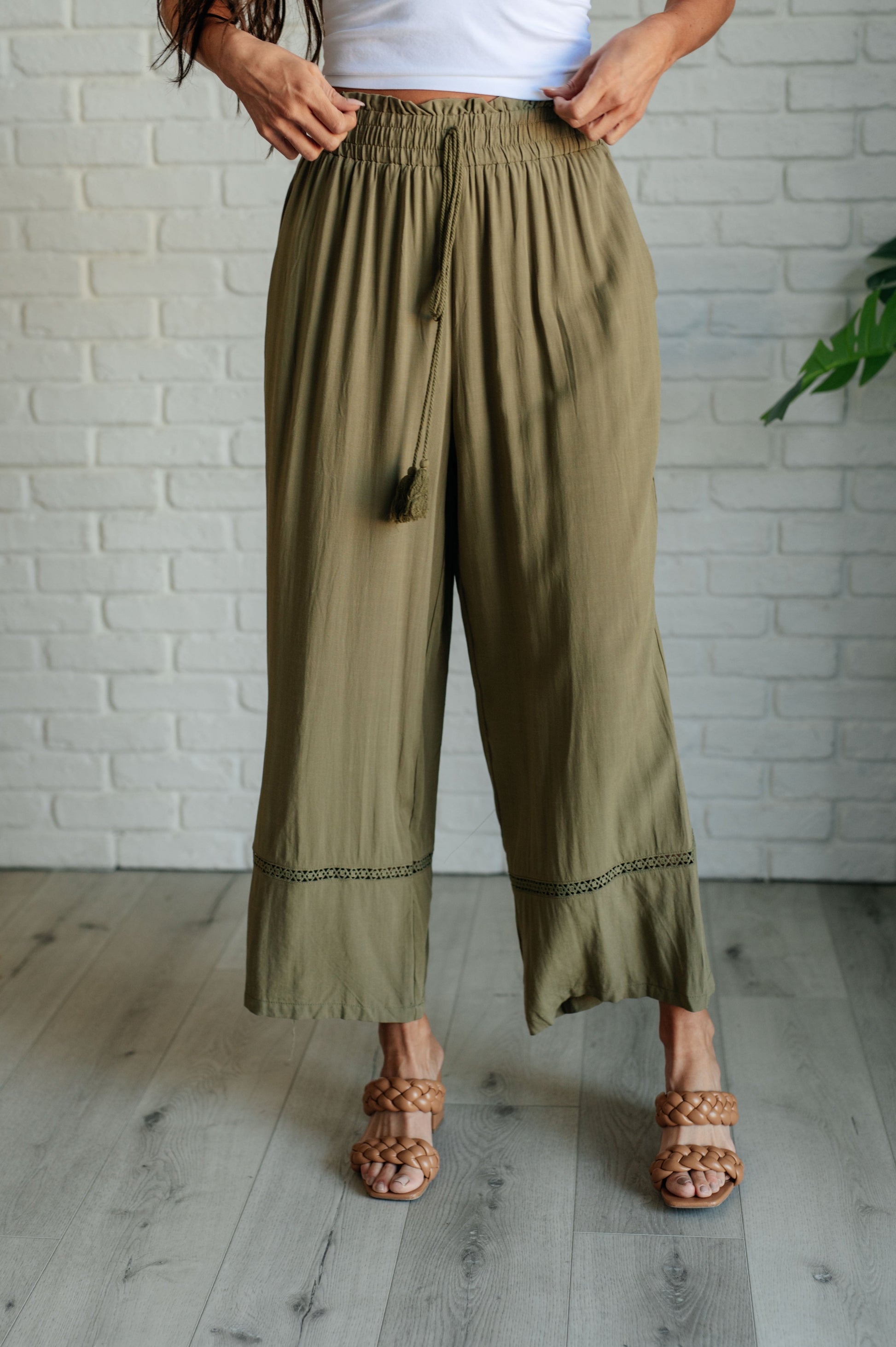 Olive wide-leg pants with a ruffled elastic waistband, geometric embroidery, and tasseled drawstring