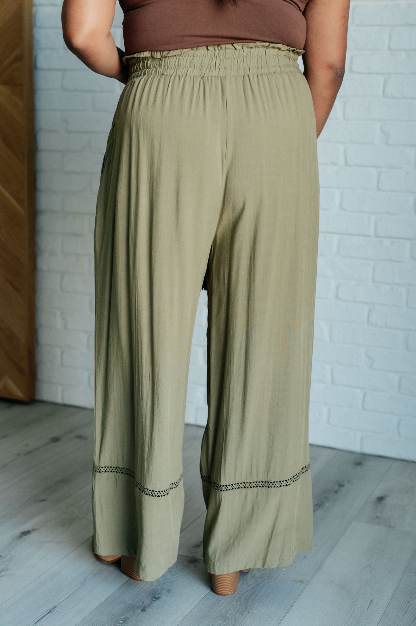 Olive wide-leg pants with a ruffled elastic waistband, geometric embroidery, and tasseled drawstring