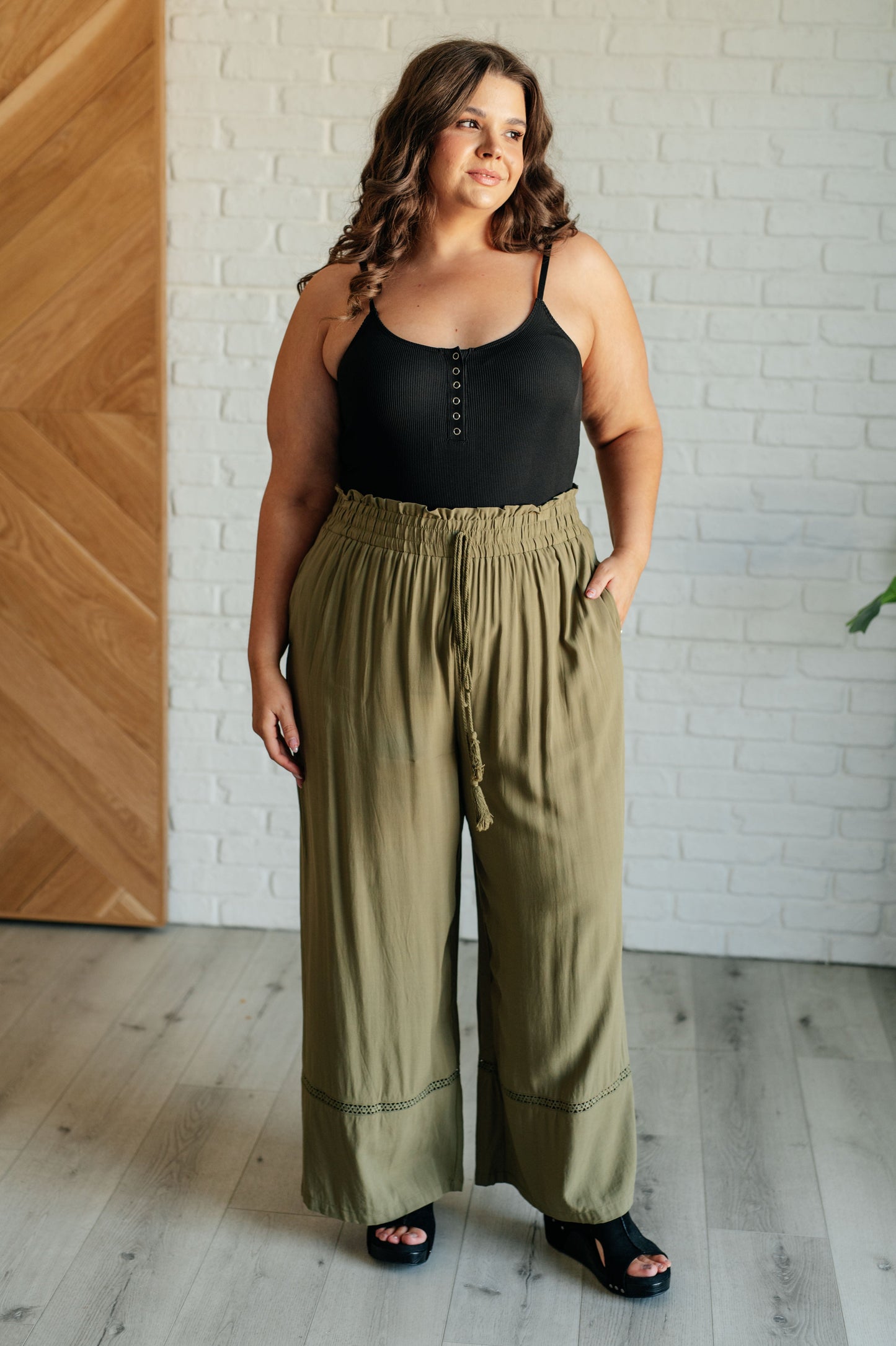 Olive wide-leg pants with a ruffled elastic waistband, geometric embroidery, and tasseled drawstring