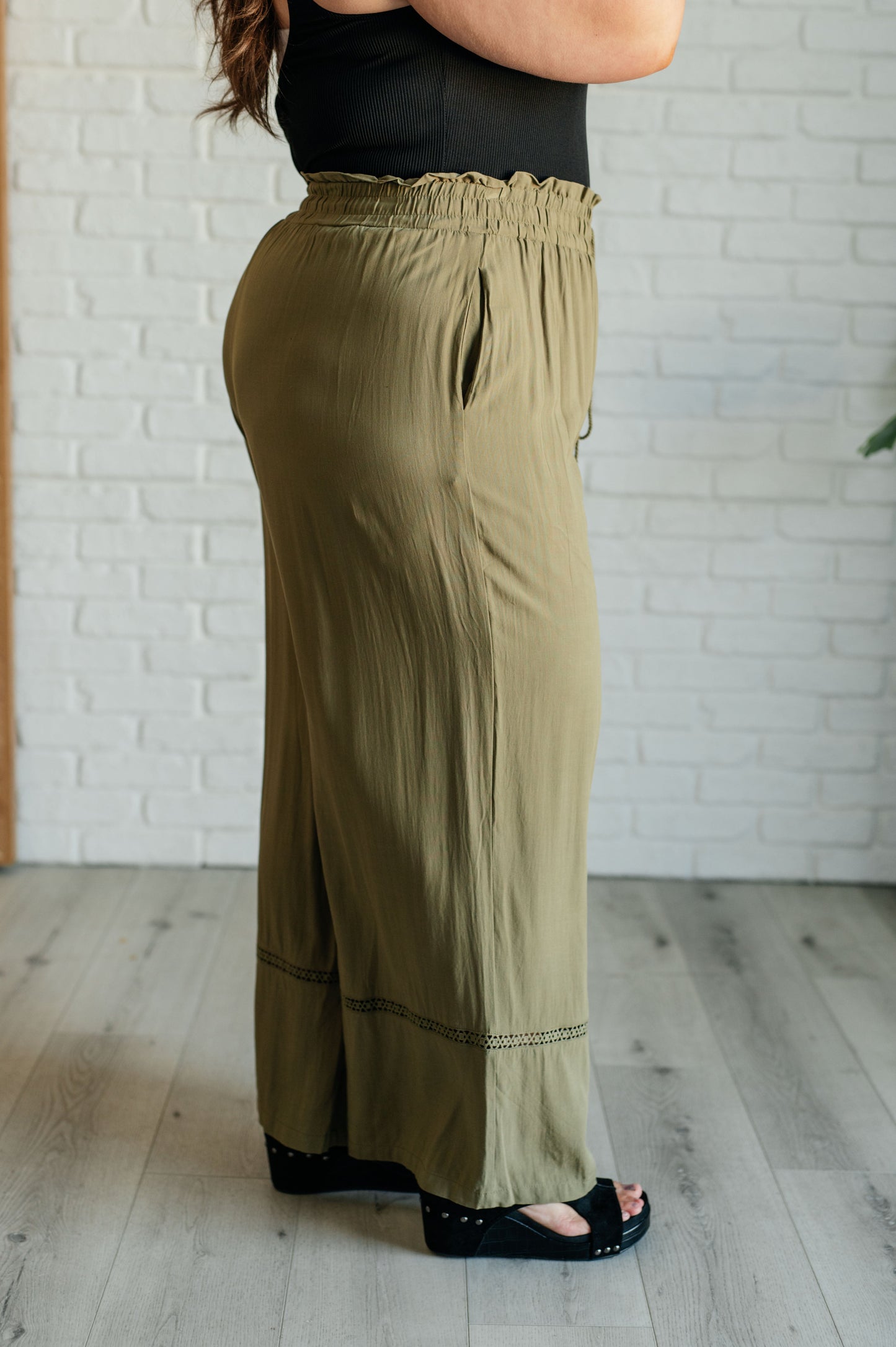 Olive wide-leg pants with a ruffled elastic waistband, geometric embroidery, and tasseled drawstring