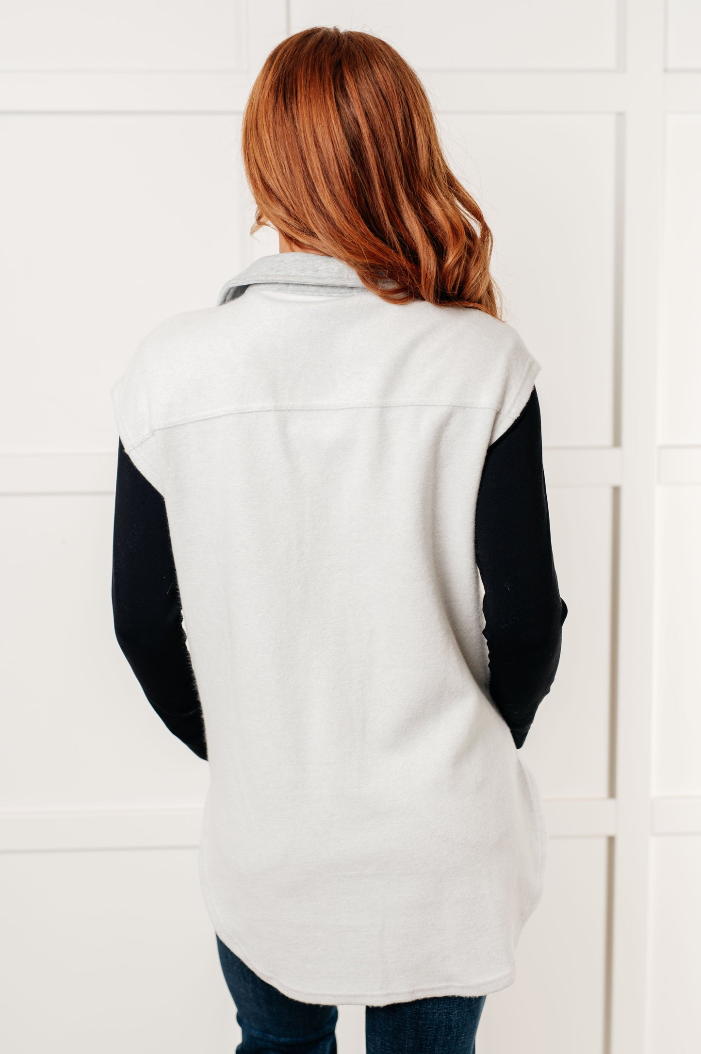 Women's Sleeveless Shacket in white with heather grey accents, featuring a collared neckline, full front button closure, chest patch pockets, and a scooped hemline. Made from soft poly cotton fleece.