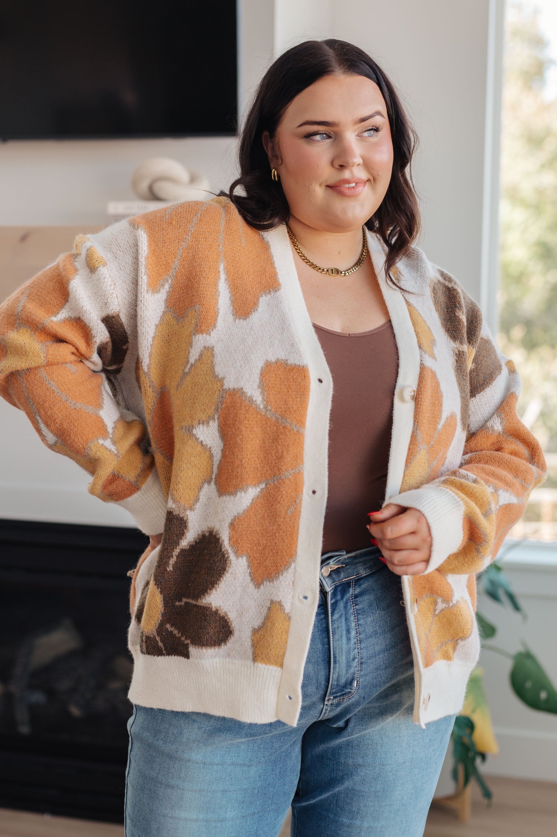  Women's floral sweater in brown, cream, orange, and yellow, featuring a V-neckline, long drop-shoulder sleeves, ribbed hem and cuffs, and a relaxed fit. Made from sweater knit fabric.