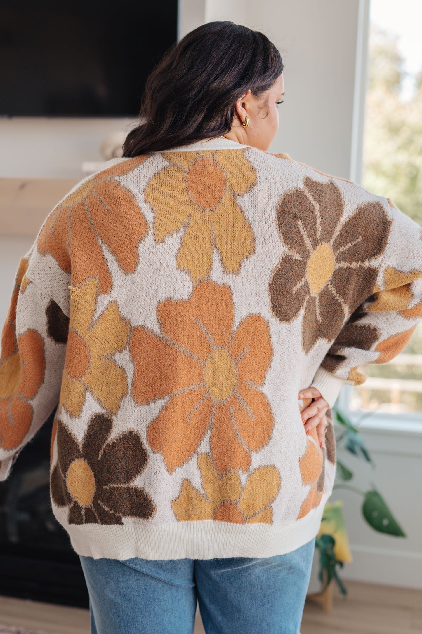  Women's floral sweater in brown, cream, orange, and yellow, featuring a V-neckline, long drop-shoulder sleeves, ribbed hem and cuffs, and a relaxed fit. Made from sweater knit fabric.