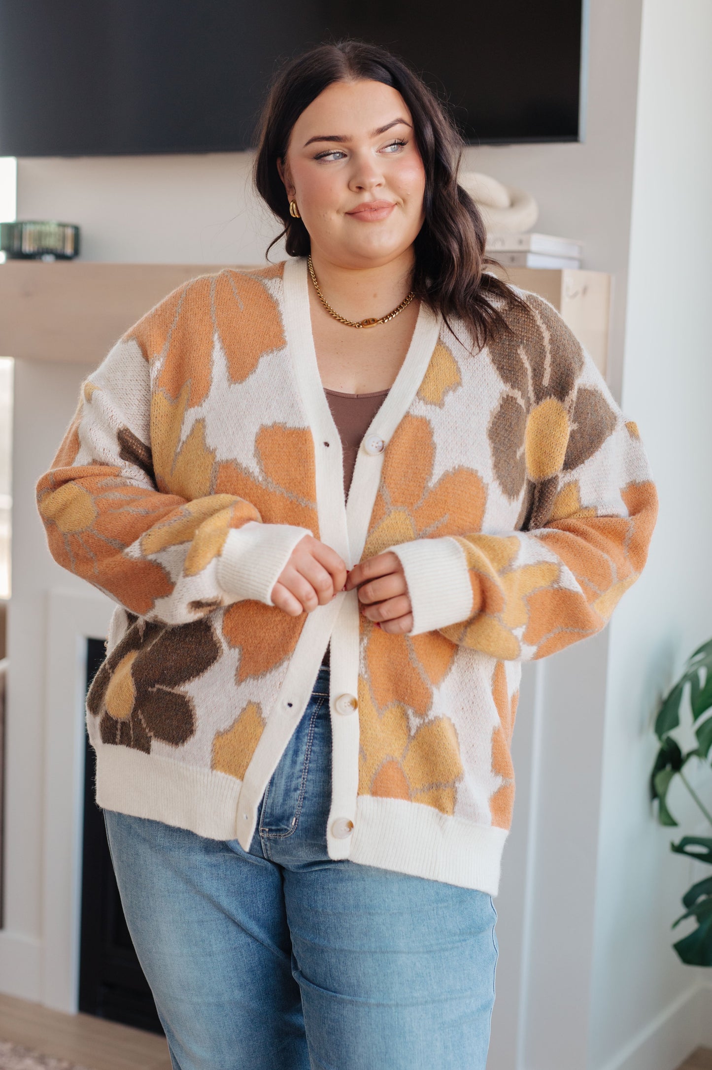  Women's floral sweater in brown, cream, orange, and yellow, featuring a V-neckline, long drop-shoulder sleeves, ribbed hem and cuffs, and a relaxed fit. Made from sweater knit fabric.