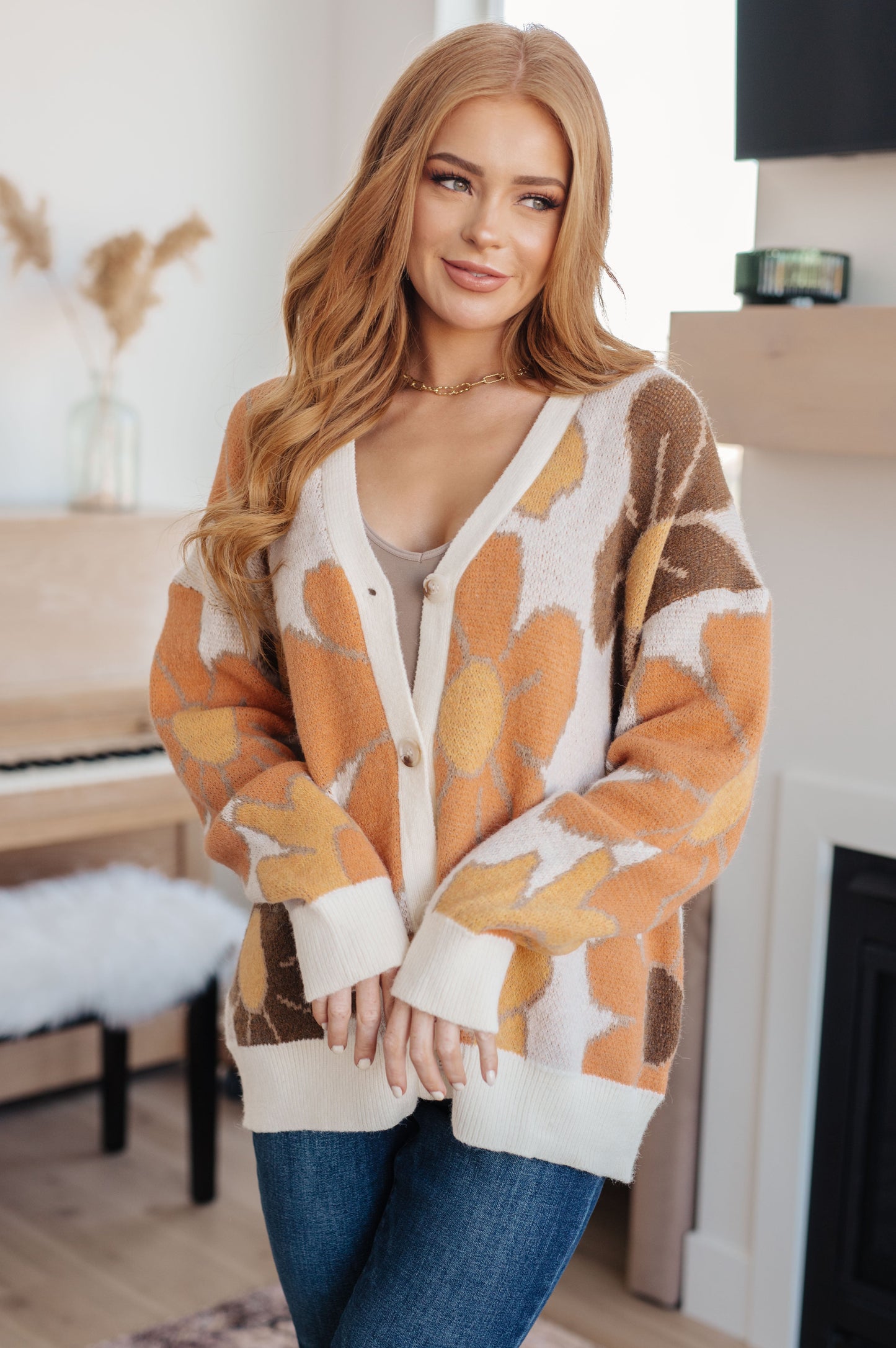  Women's floral sweater in brown, cream, orange, and yellow, featuring a V-neckline, long drop-shoulder sleeves, ribbed hem and cuffs, and a relaxed fit. Made from sweater knit fabric.