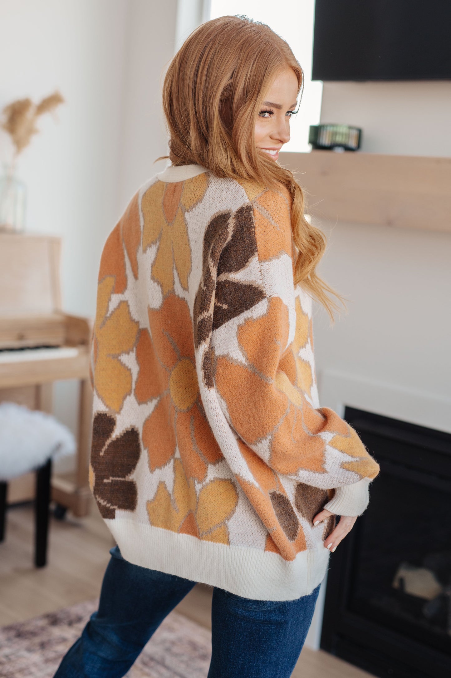  Women's floral sweater in brown, cream, orange, and yellow, featuring a V-neckline, long drop-shoulder sleeves, ribbed hem and cuffs, and a relaxed fit. Made from sweater knit fabric.