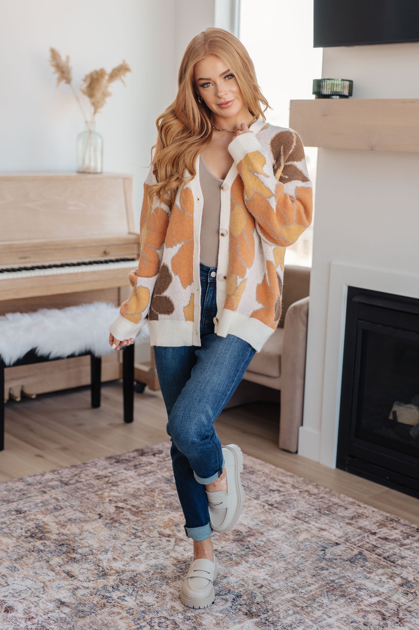  Women's floral sweater in brown, cream, orange, and yellow, featuring a V-neckline, long drop-shoulder sleeves, ribbed hem and cuffs, and a relaxed fit. Made from sweater knit fabric.