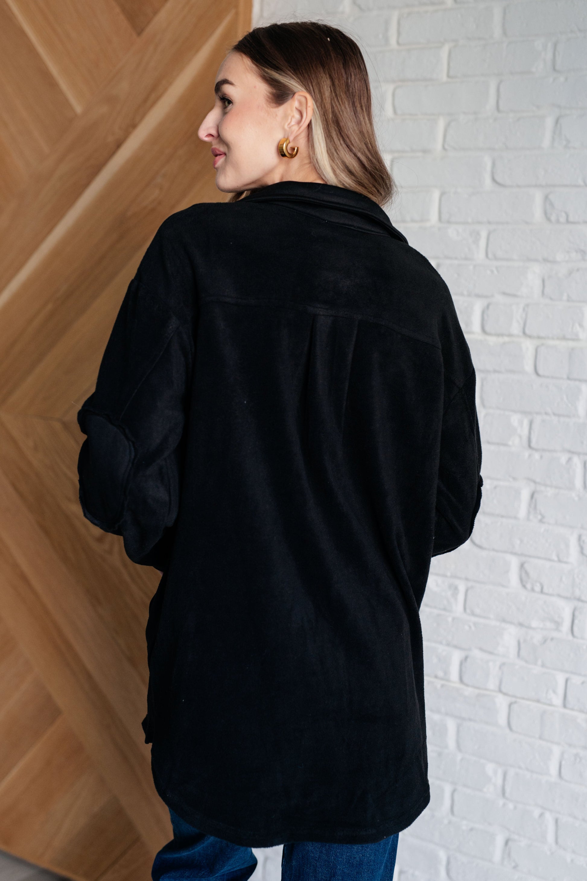 Black fleece jacket with a collared neckline, contrast panels, elbow patches, functional button closures, and banded sleeve cuffs. Features chest patch and side welt pockets.