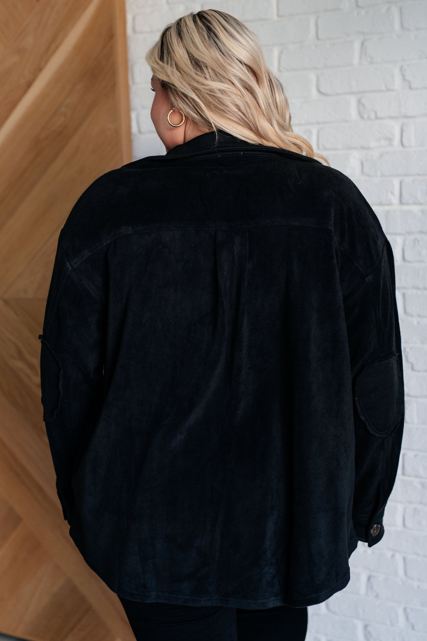 Black fleece jacket with a collared neckline, contrast panels, elbow patches, functional button closures, and banded sleeve cuffs. Features chest patch and side welt pockets.