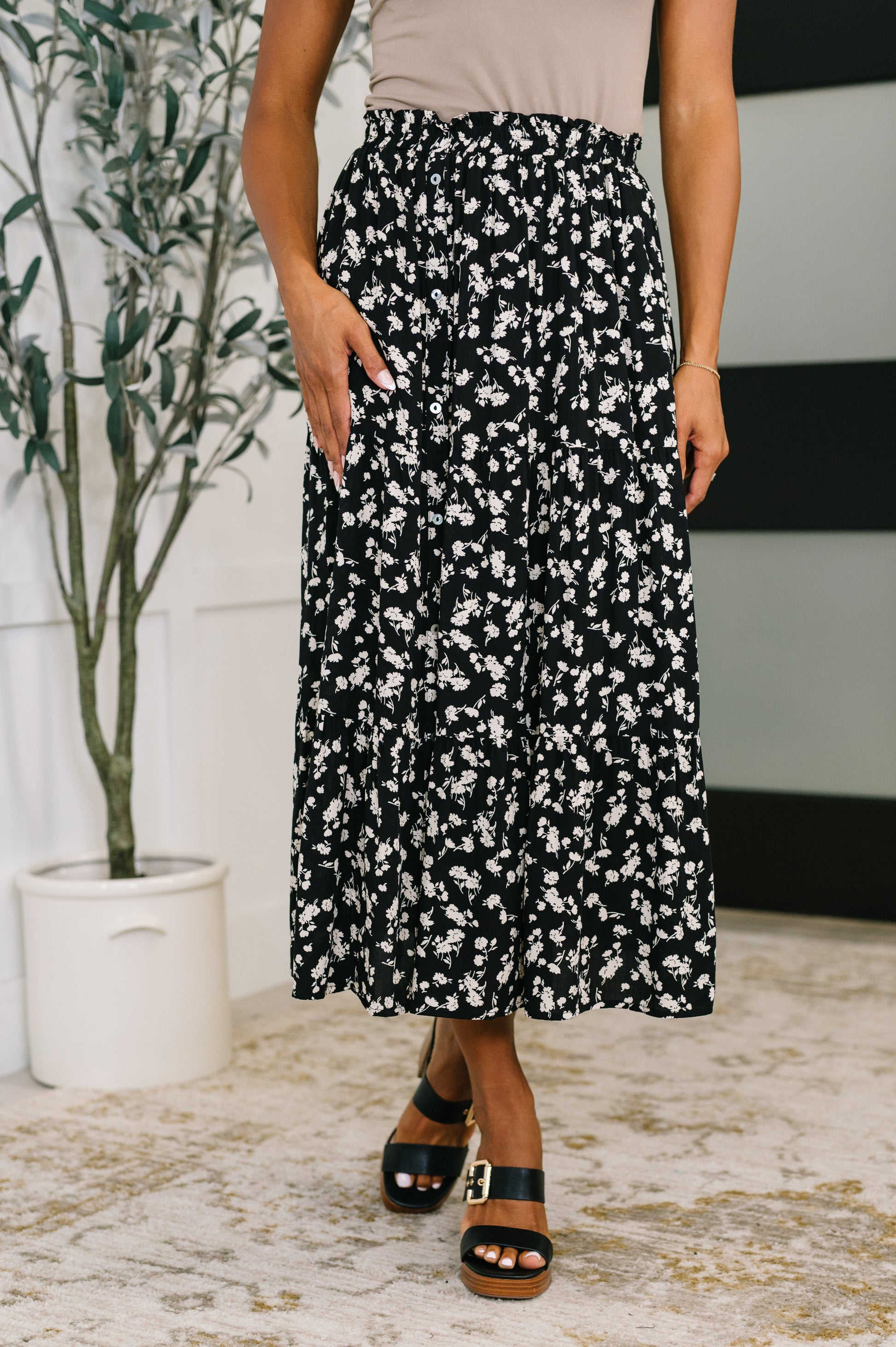 Model wearing Virginia Floral Skirt in black with white ditsy print and tiered design.