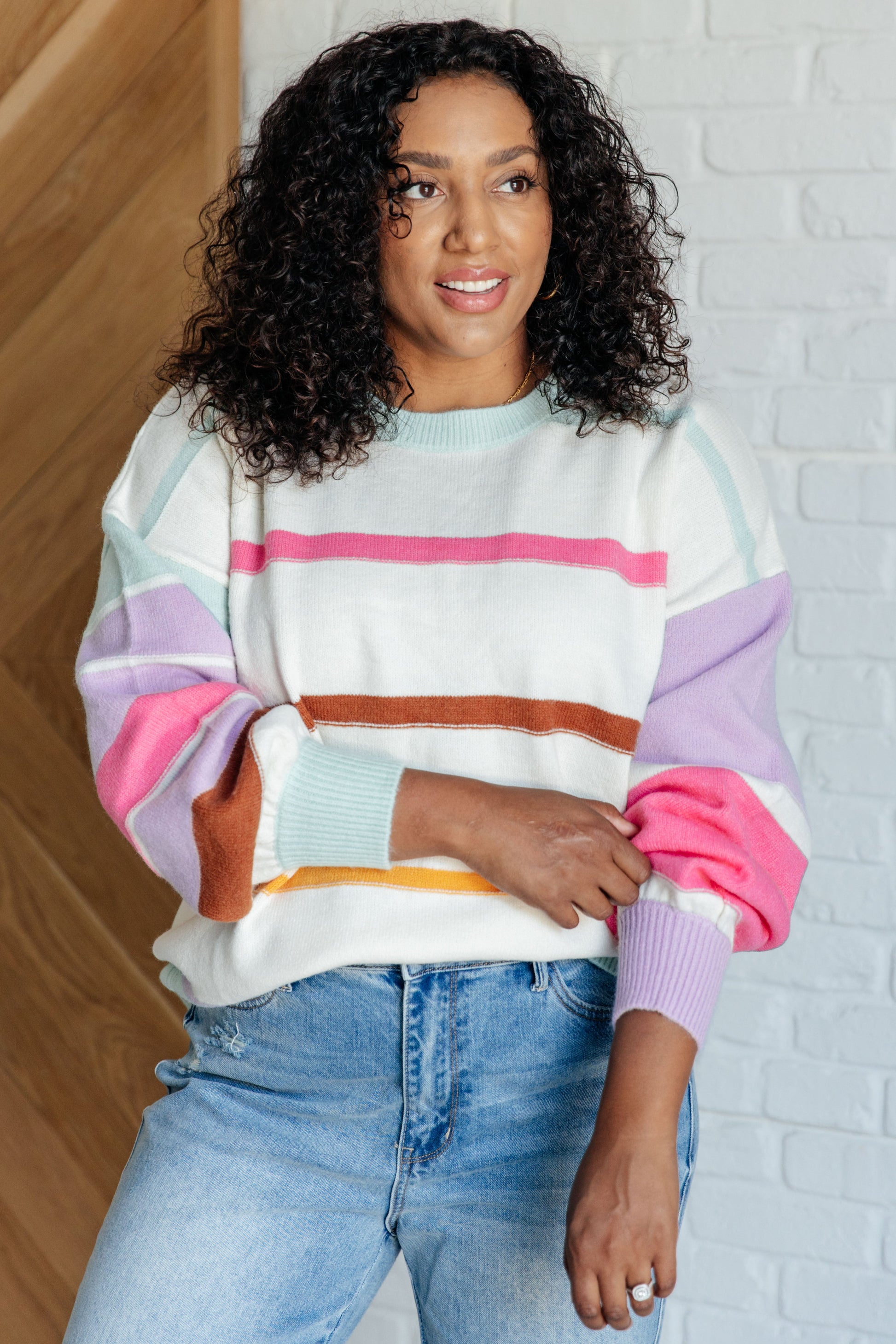 Women's multi-colored striped sweater made from lightweight sweater knit. With a ribbed rounded neckline, long balloon sleeves with drop shoulder, and ribbed sleeve cuffs and hemline.