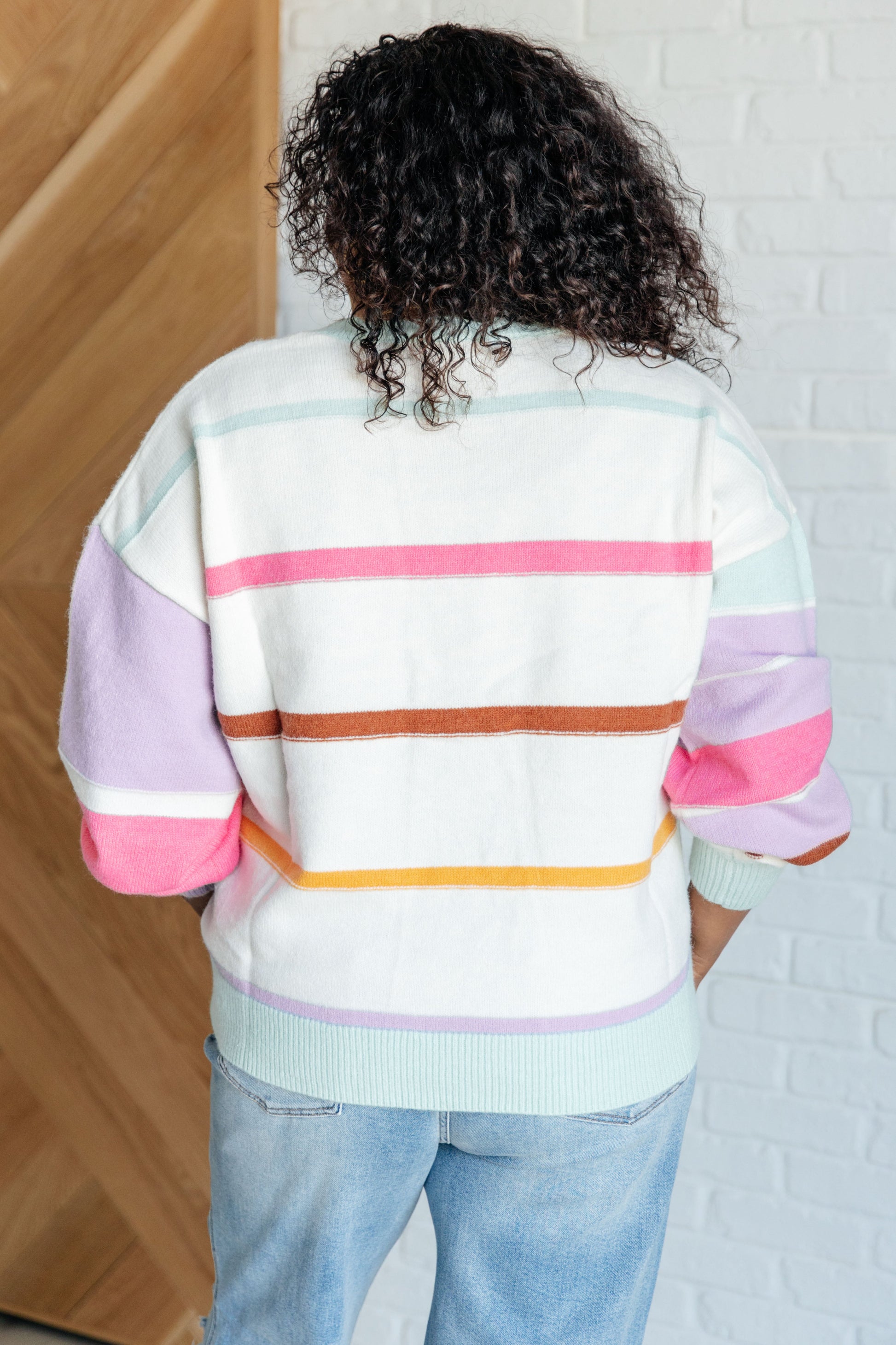 Women's multi-colored striped sweater made from lightweight sweater knit. With a ribbed rounded neckline, long balloon sleeves with drop shoulder, and ribbed sleeve cuffs and hemline.