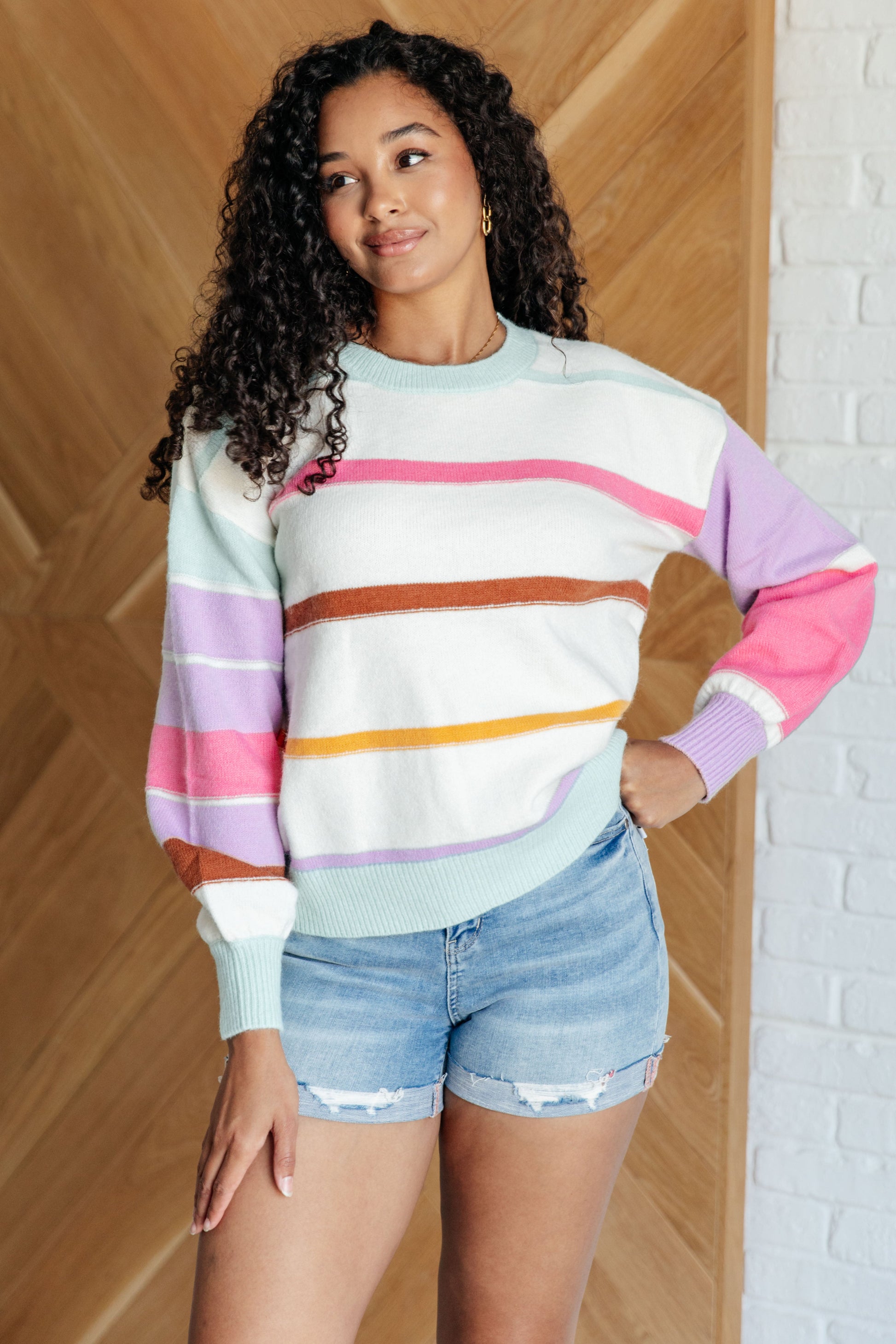 Women's multi-colored striped sweater made from lightweight sweater knit. With a ribbed rounded neckline, long balloon sleeves with drop shoulder, and ribbed sleeve cuffs and hemline.