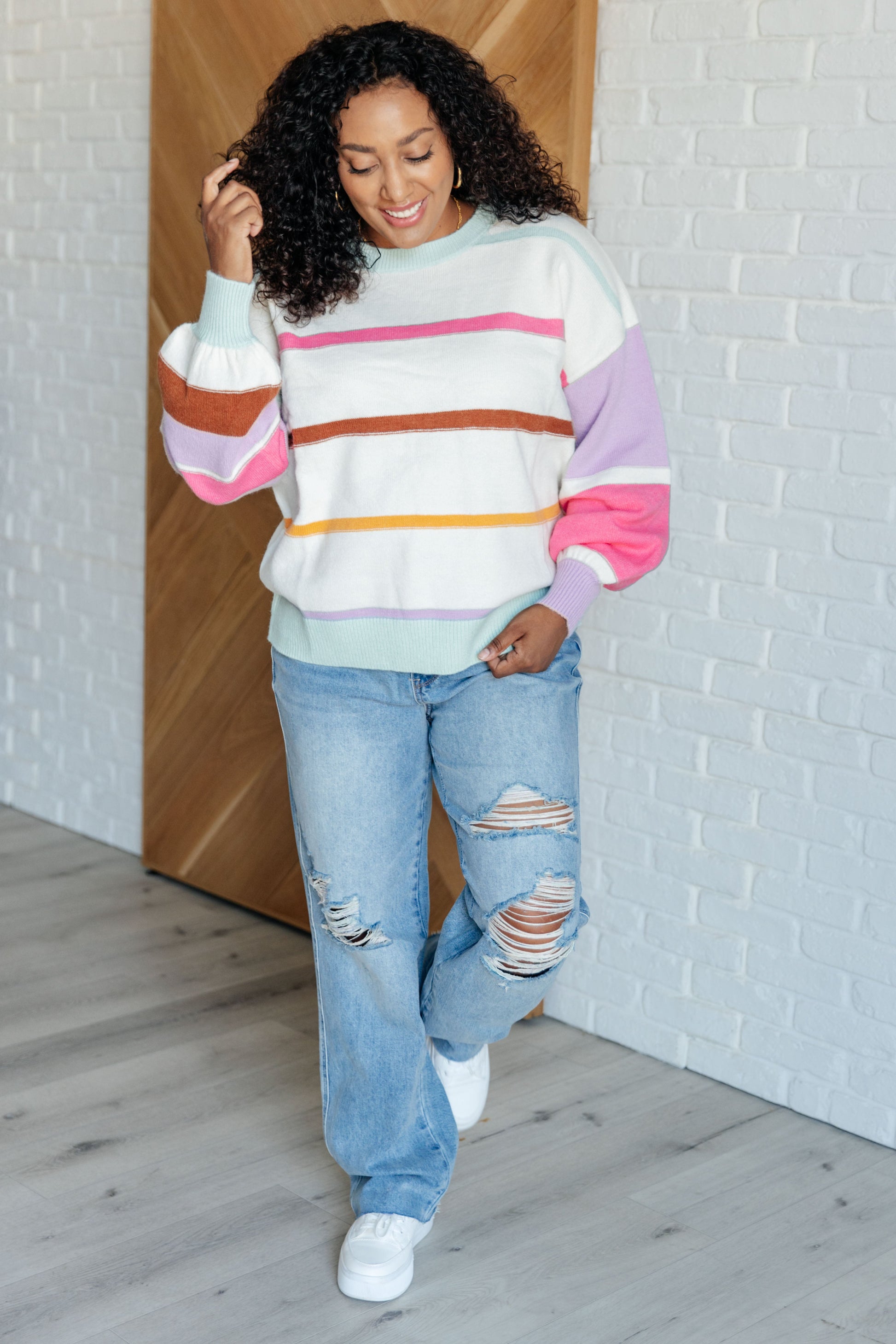 Women's multi-colored striped sweater made from lightweight sweater knit. With a ribbed rounded neckline, long balloon sleeves with drop shoulder, and ribbed sleeve cuffs and hemline.