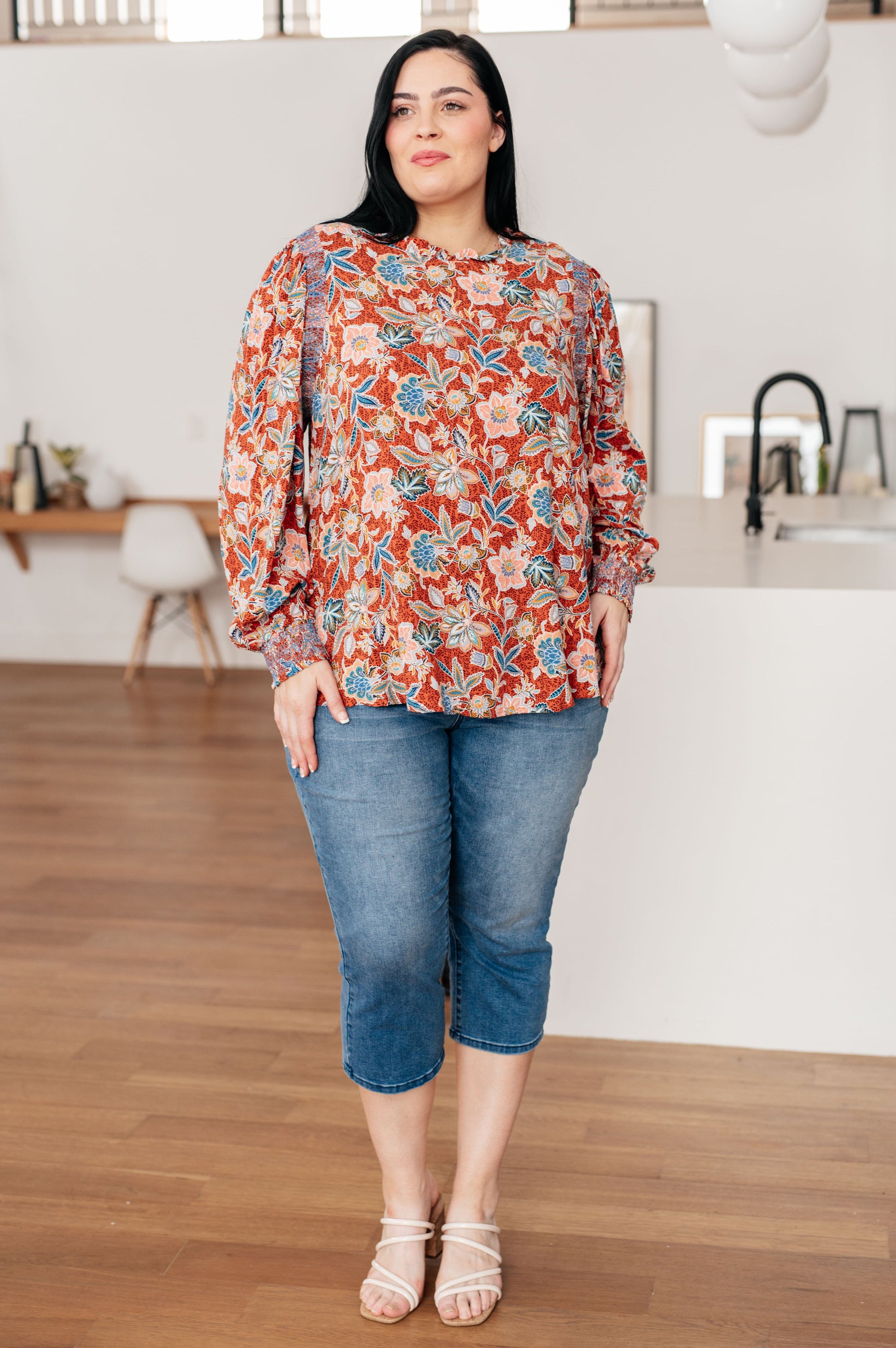 Plus size full body view of Blair Floral Blouse with rust base, teal and peach floral print, and smocked accents.