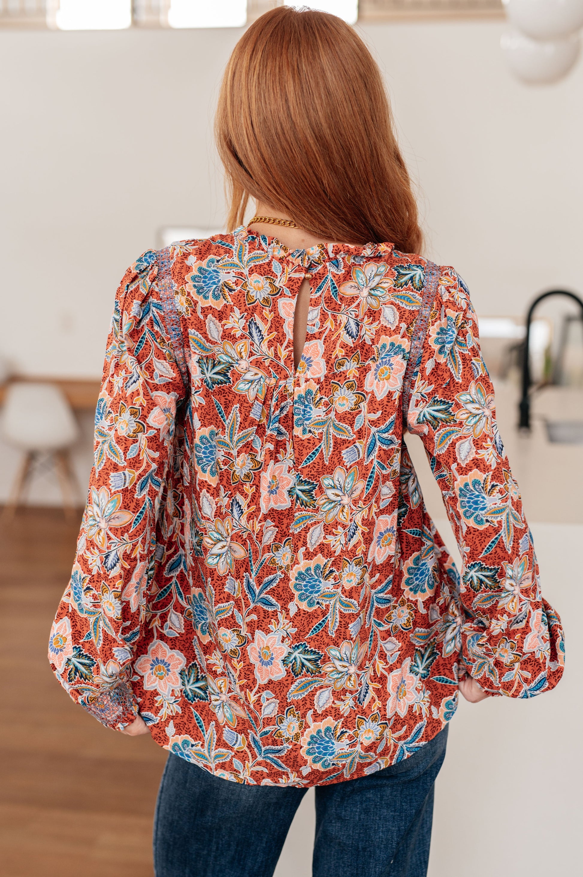 Back view of Blair Floral Blouse showing rust floral print with peach and teal flowers on lightweight rayon