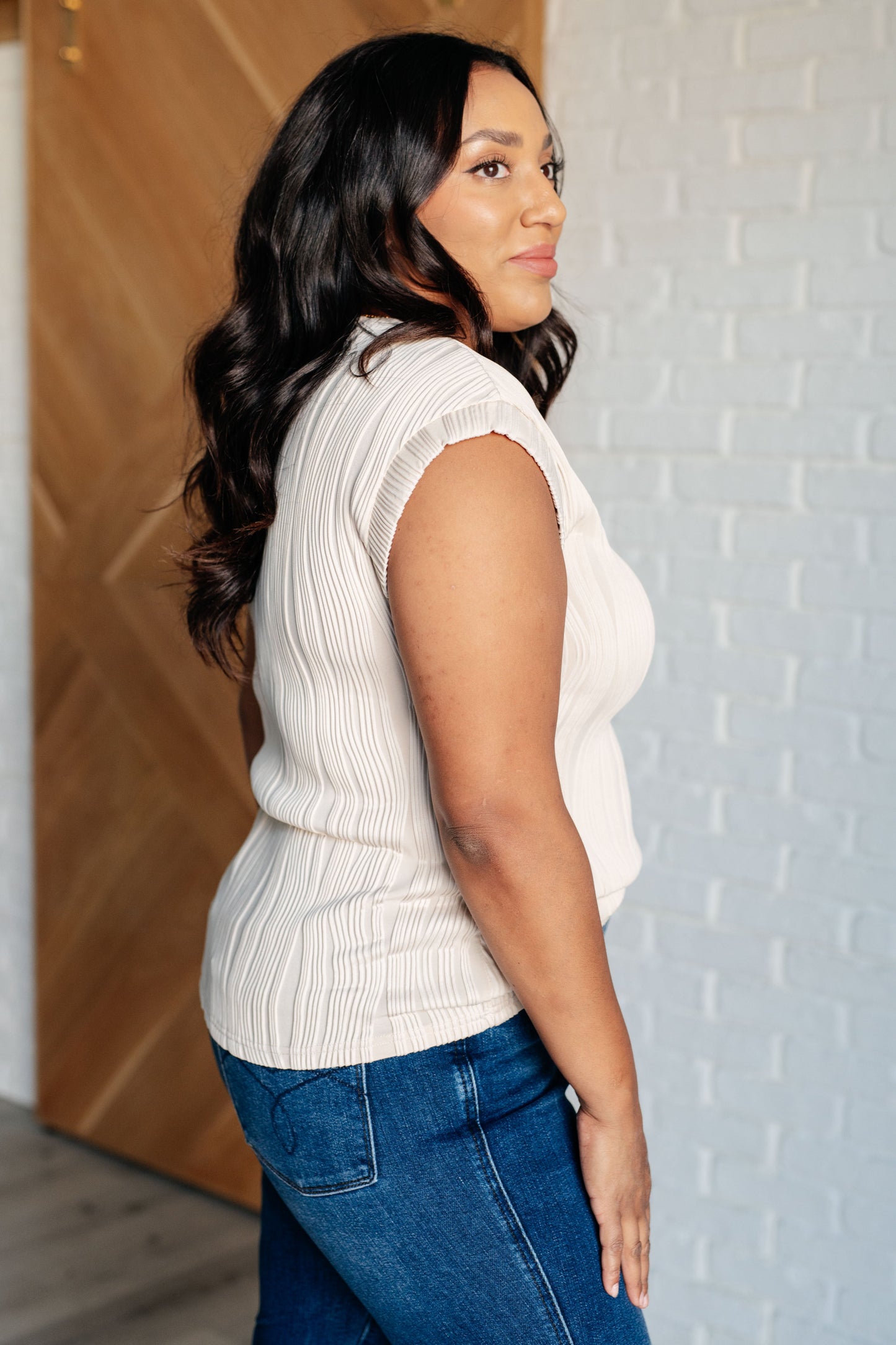 Beige embossed knit top with banded round neckline and short sleeves with banded cuffs. Features a muscle tee fit.