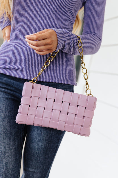 Woman holding Lilia Basket Weave Lilac Purse by brushed gold chain handle, basket weave texture shown.