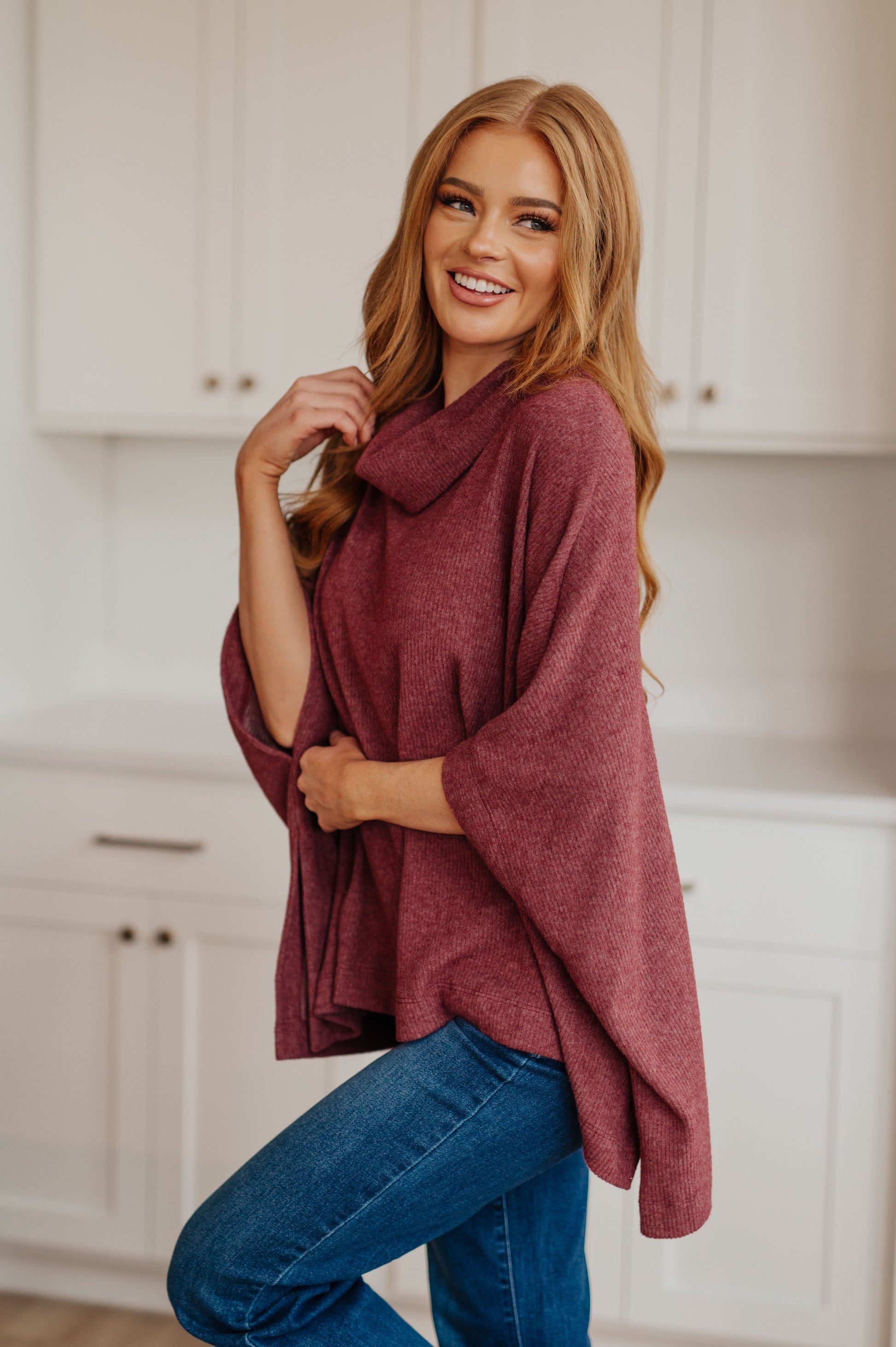 Women's dark mauve poncho made from brushed ribbed hacci knit fabric, featuring a cowl neckline, poncho silhouette, side slit, and a relaxed fit.