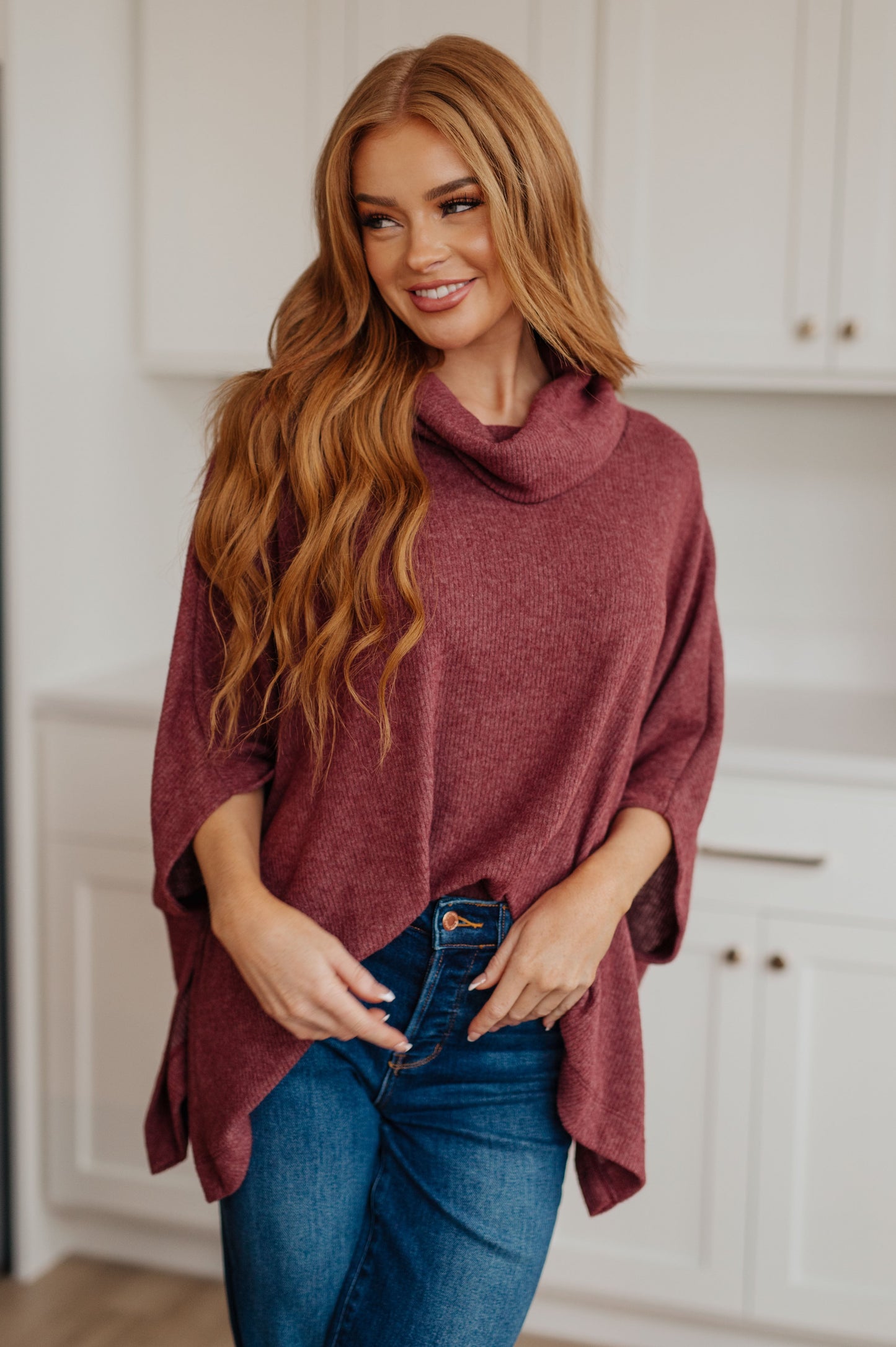 Women's dark mauve poncho made from brushed ribbed hacci knit fabric, featuring a cowl neckline, poncho silhouette, side slit, and a relaxed fit.