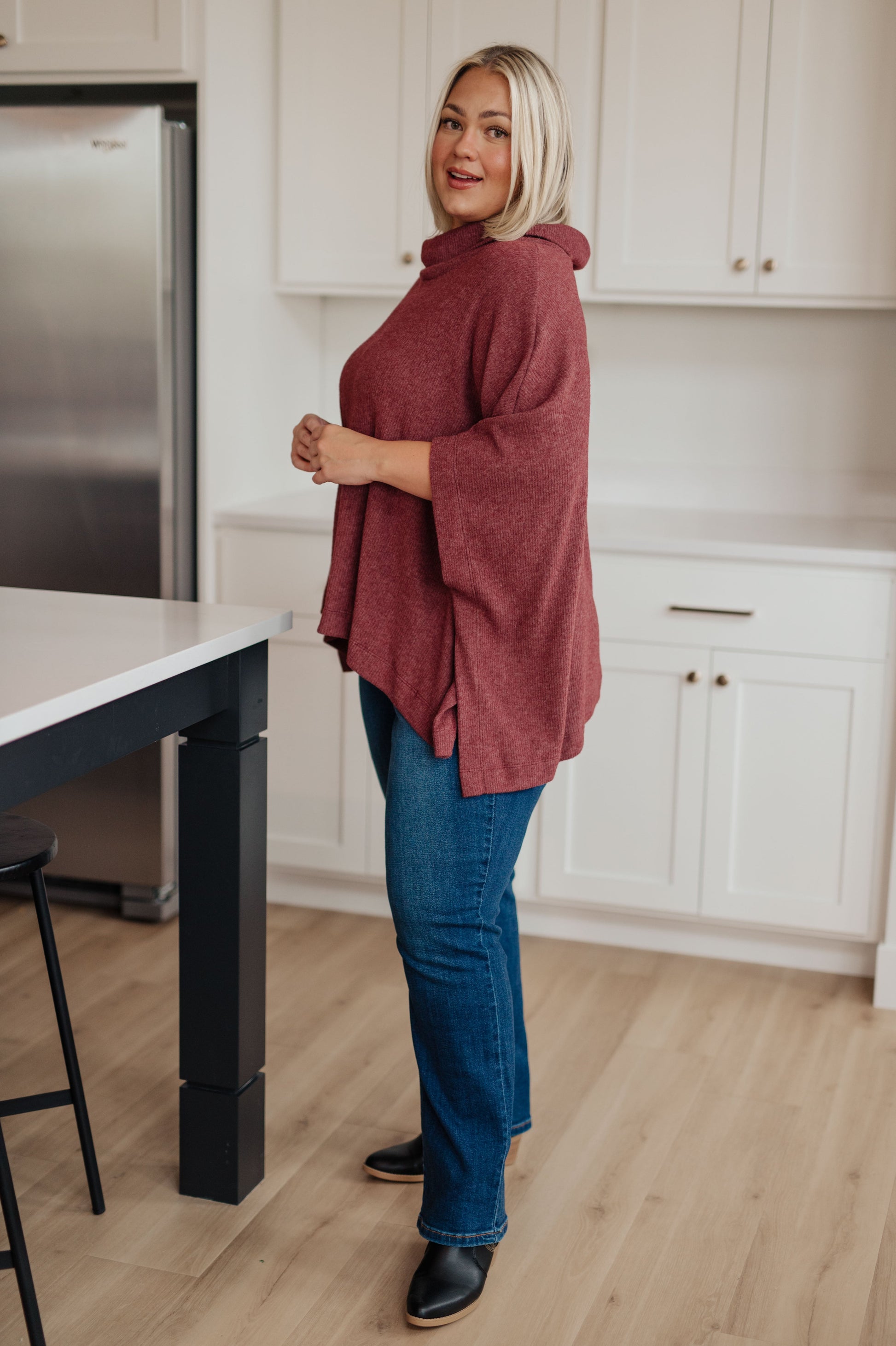 Women's dark mauve poncho made from brushed ribbed hacci knit fabric, featuring a cowl neckline, poncho silhouette, side slit, and a relaxed fit.