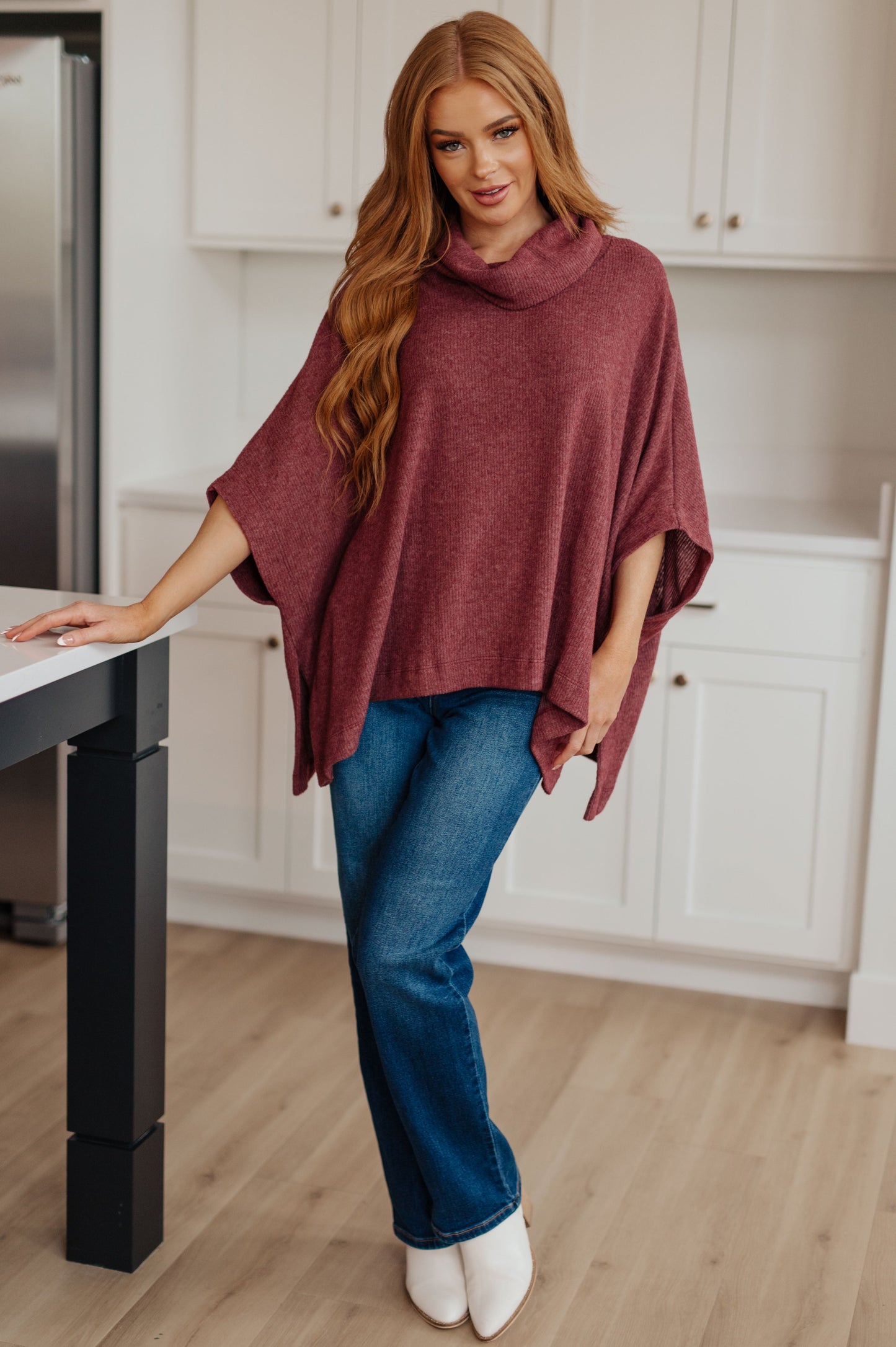 Women's dark mauve poncho made from brushed ribbed hacci knit fabric, featuring a cowl neckline, poncho silhouette, side slit, and a relaxed fit.