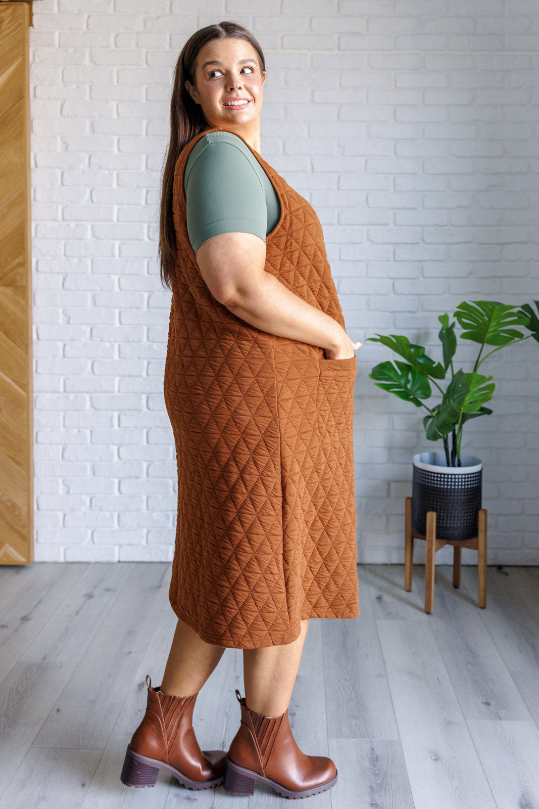 Caramel quilted knit jumper-style midi dress with a scoop neckline, sleeveless design, A-line fit, and patch pockets.