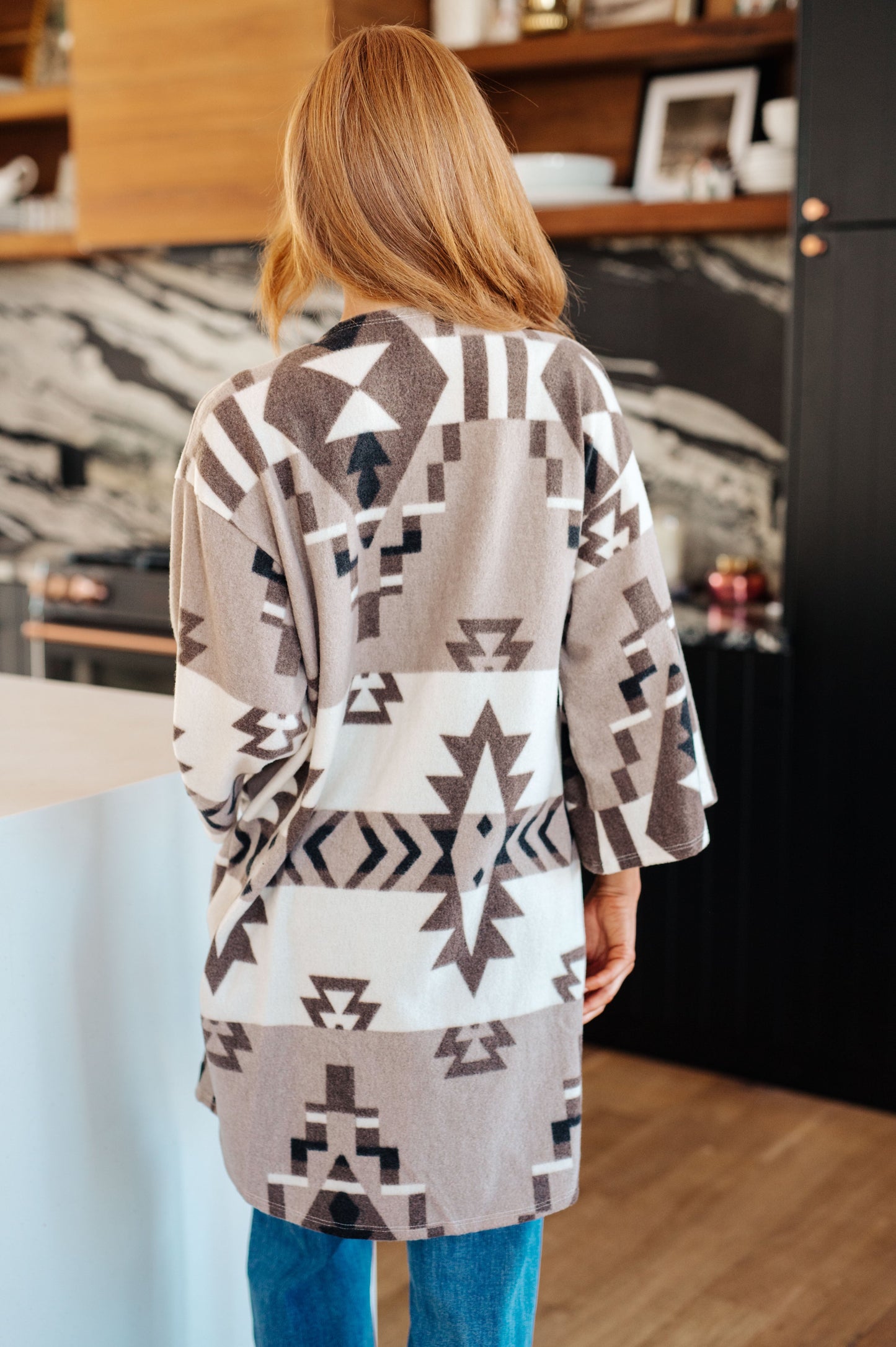 Women's blanket kimono cardigan in gray, brown, white and black with a geometric print. Made from brushed hacci fabric, featuring 3/4 sleeves, a drop shoulder, and an open front neckline.