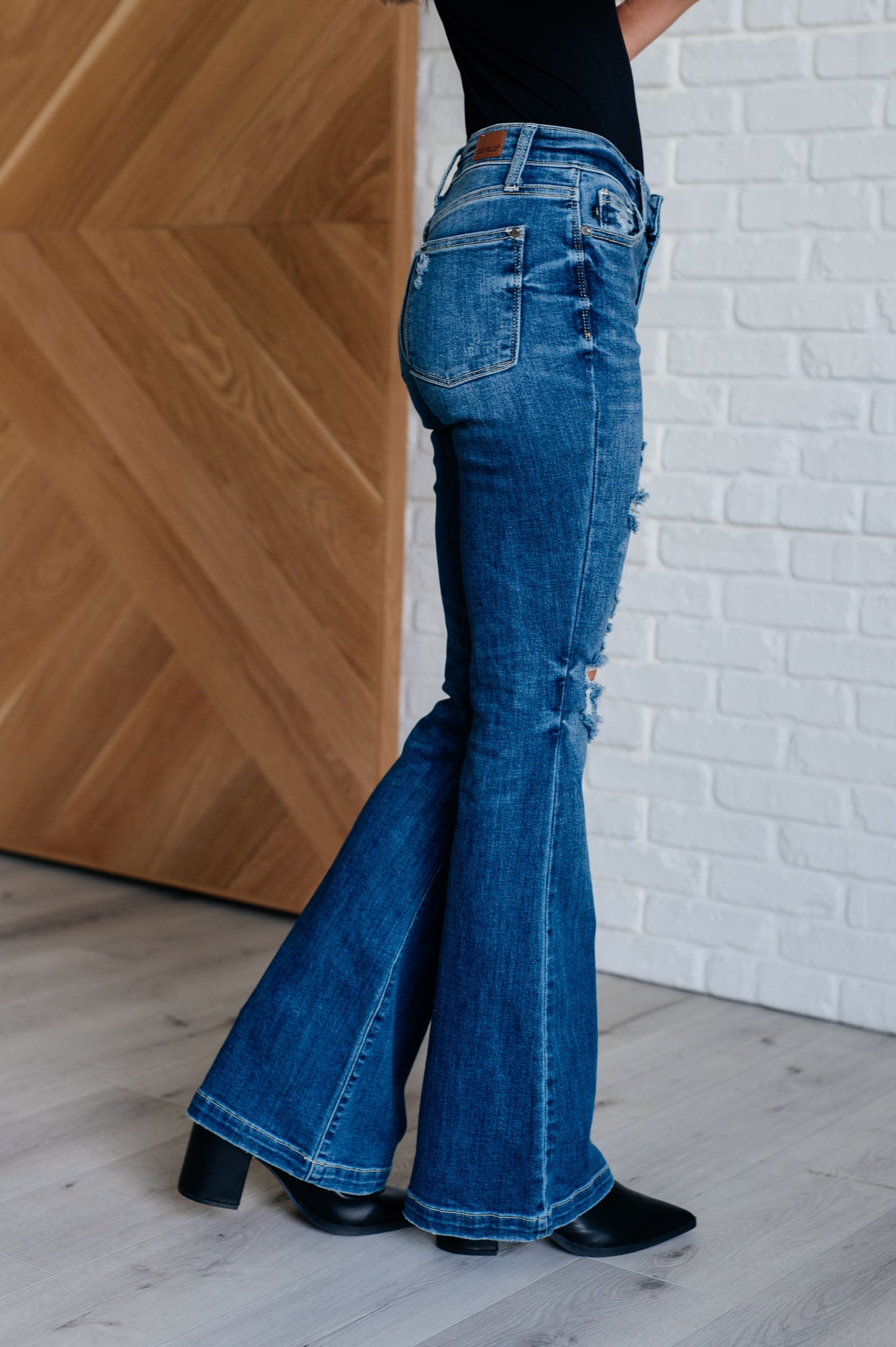 Distressed Button Fly Flare Jeans by Judy Blue, featuring mid-rise, button fly closure, and slight distressing on pockets and legs. Stretchy denim with a slim fit through thighs flares out at the ankle for a stylish silhouette. 