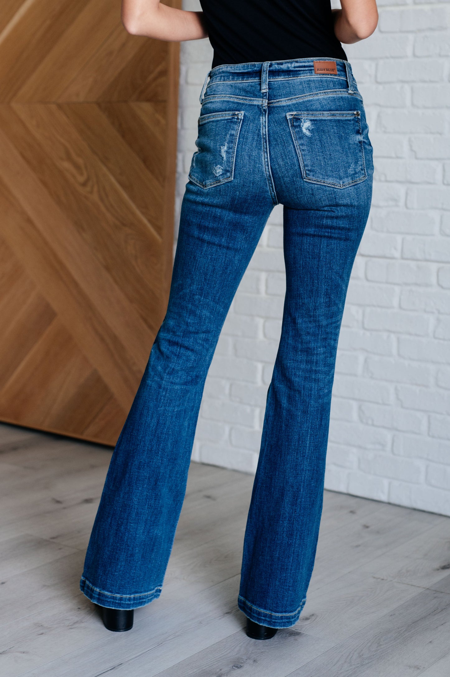 Distressed Button Fly Flare Jeans by Judy Blue, featuring mid-rise, button fly closure, and slight distressing on pockets and legs. Stretchy denim with a slim fit through thighs flares out at the ankle for a stylish silhouette. 