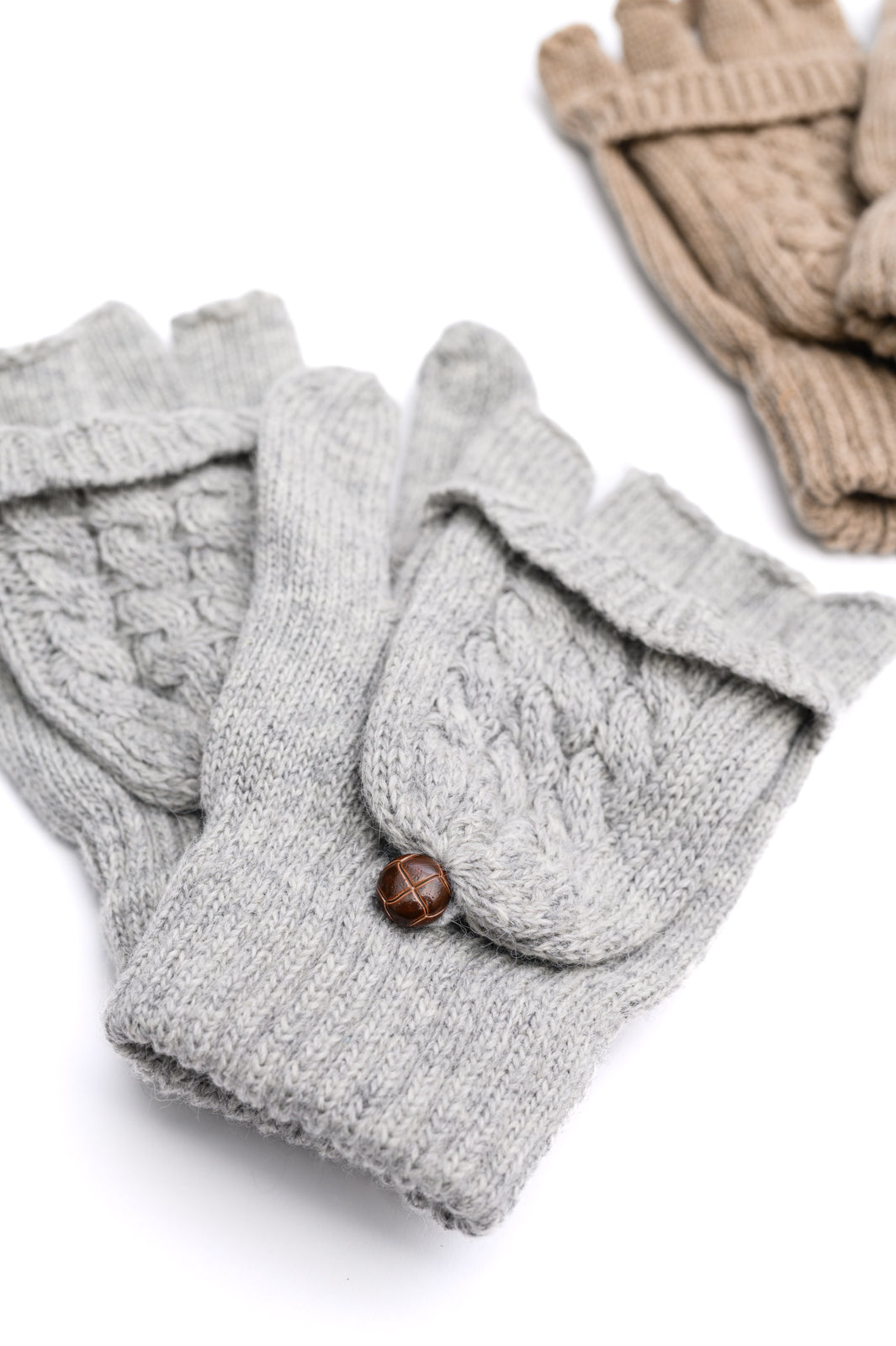 Flat lay view of women's flip-top gloves set of 2 in beige and gray, featuring a cable knit design, split finger mittens, and button closure.