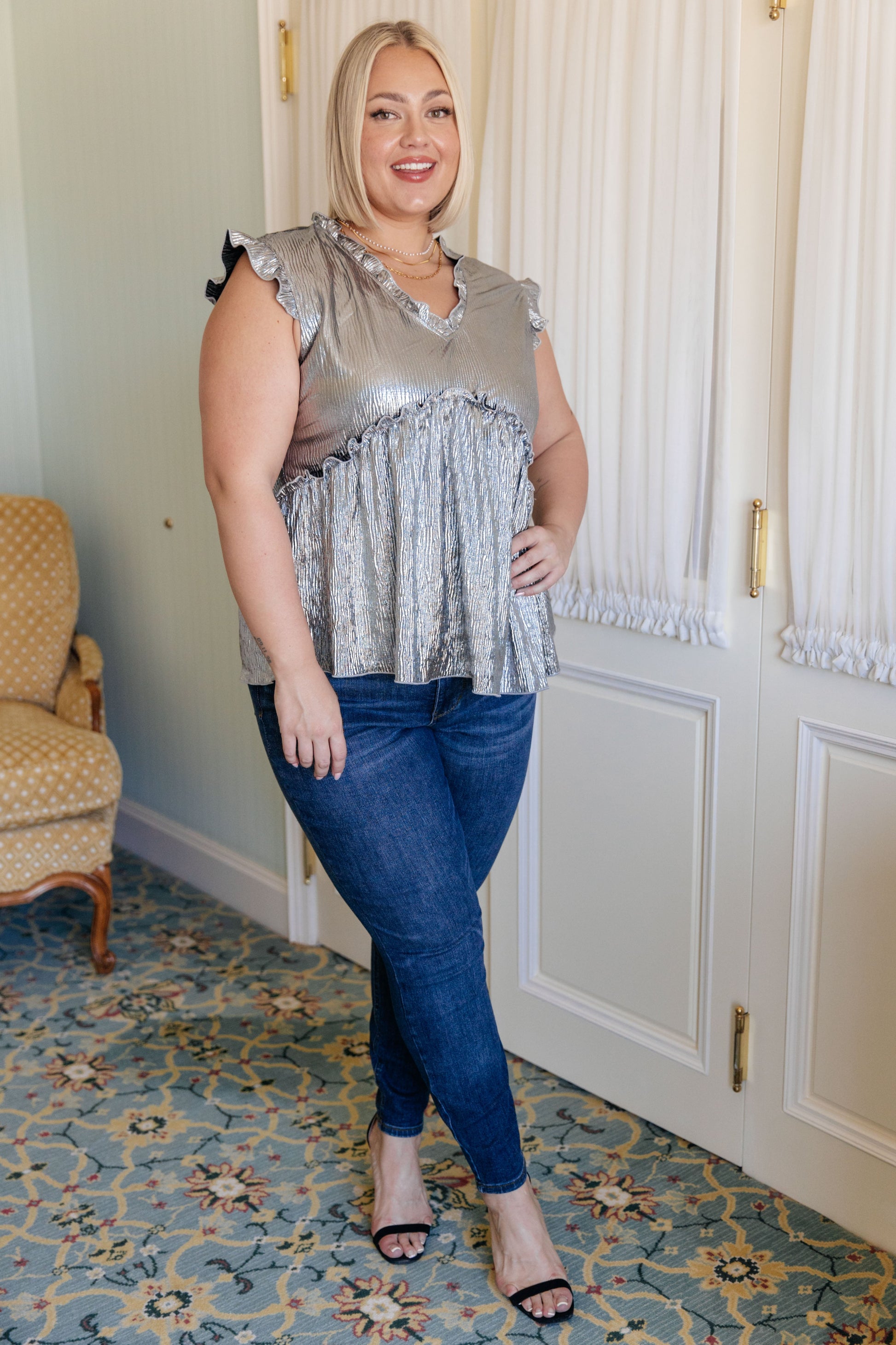 Silver metallic poly lamé peplum top with ruffled V-neckline, ruffle cap sleeves, and peplum design.