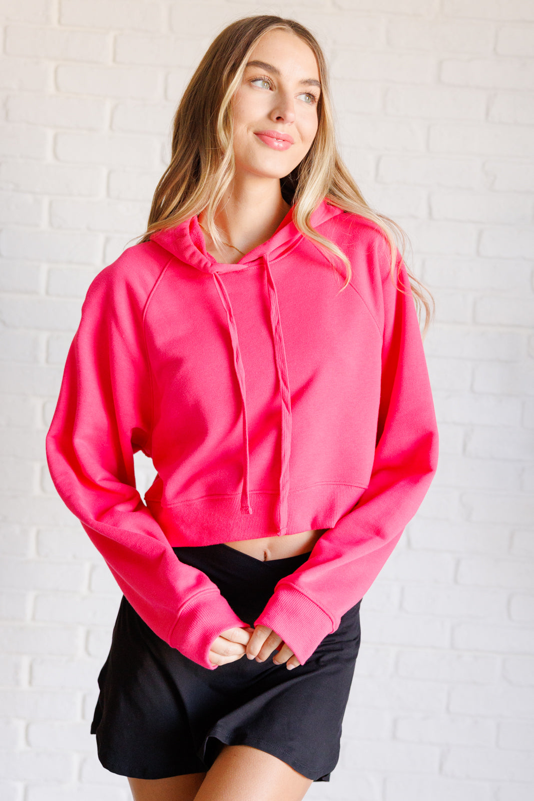 Flamingo pink French terry cropped hoodie with a hood and functional drawstring, dolman long sleeves, and banded ribbed cuffs and hemline.