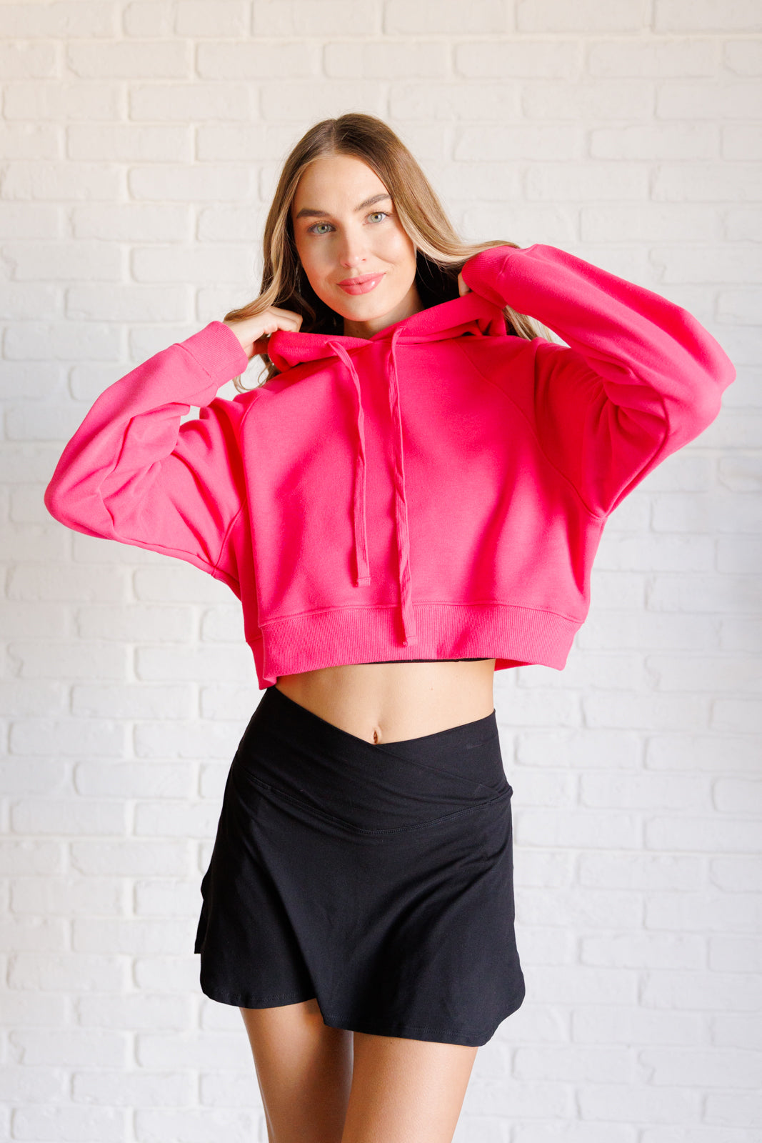 Flamingo pink French terry cropped hoodie with a hood and functional drawstring, dolman long sleeves, and banded ribbed cuffs and hemline.