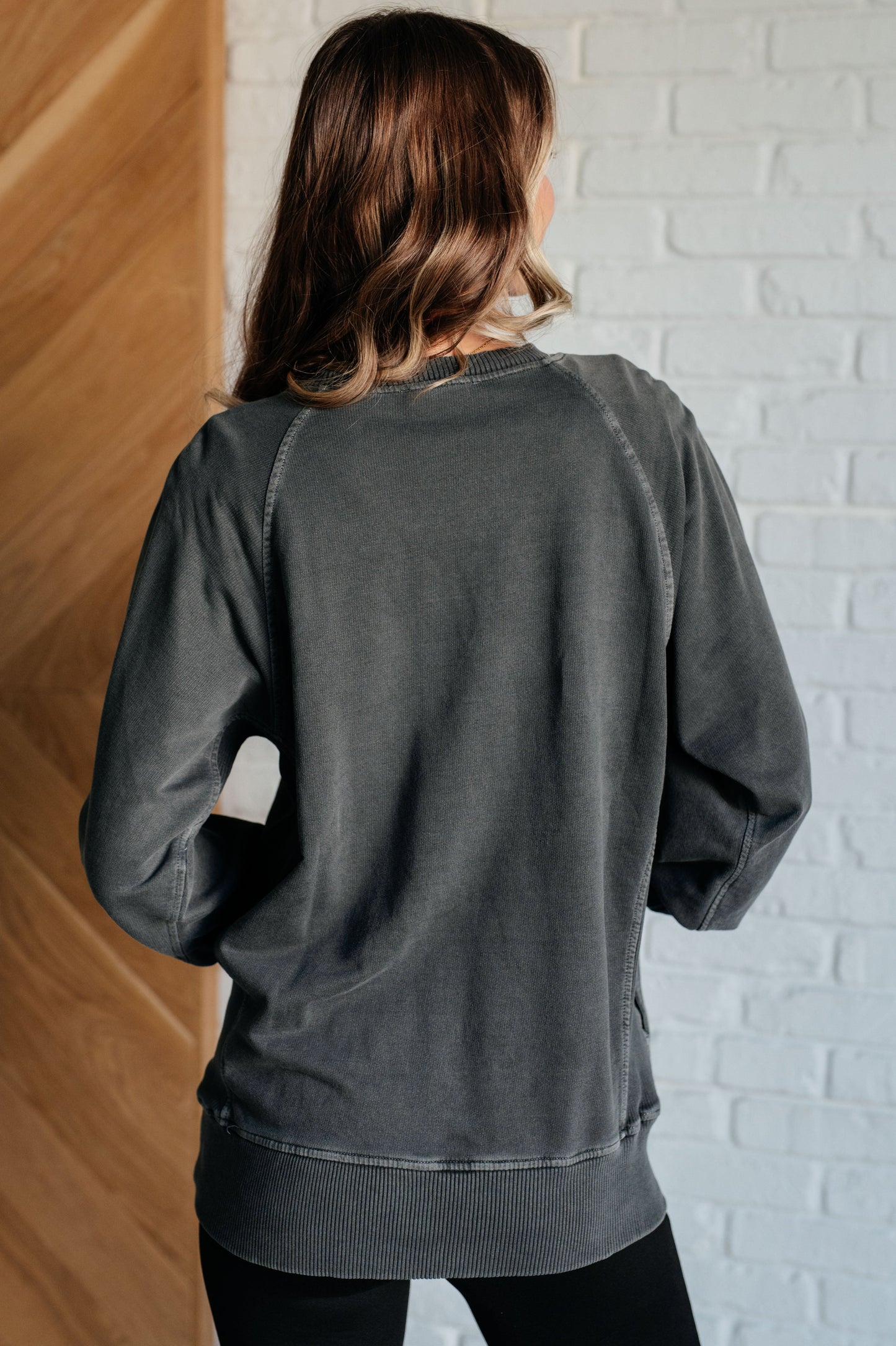 Black sweatshirt in mid-weight French terry with a round neckline, long raglan sleeves, side pockets, ribbed details, and garment-dyed finish.