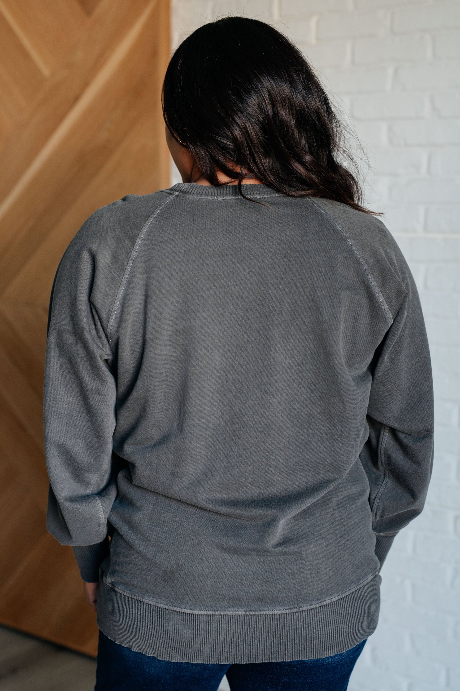 Black sweatshirt in mid-weight French terry with a round neckline, long raglan sleeves, side pockets, ribbed details, and garment-dyed finish.