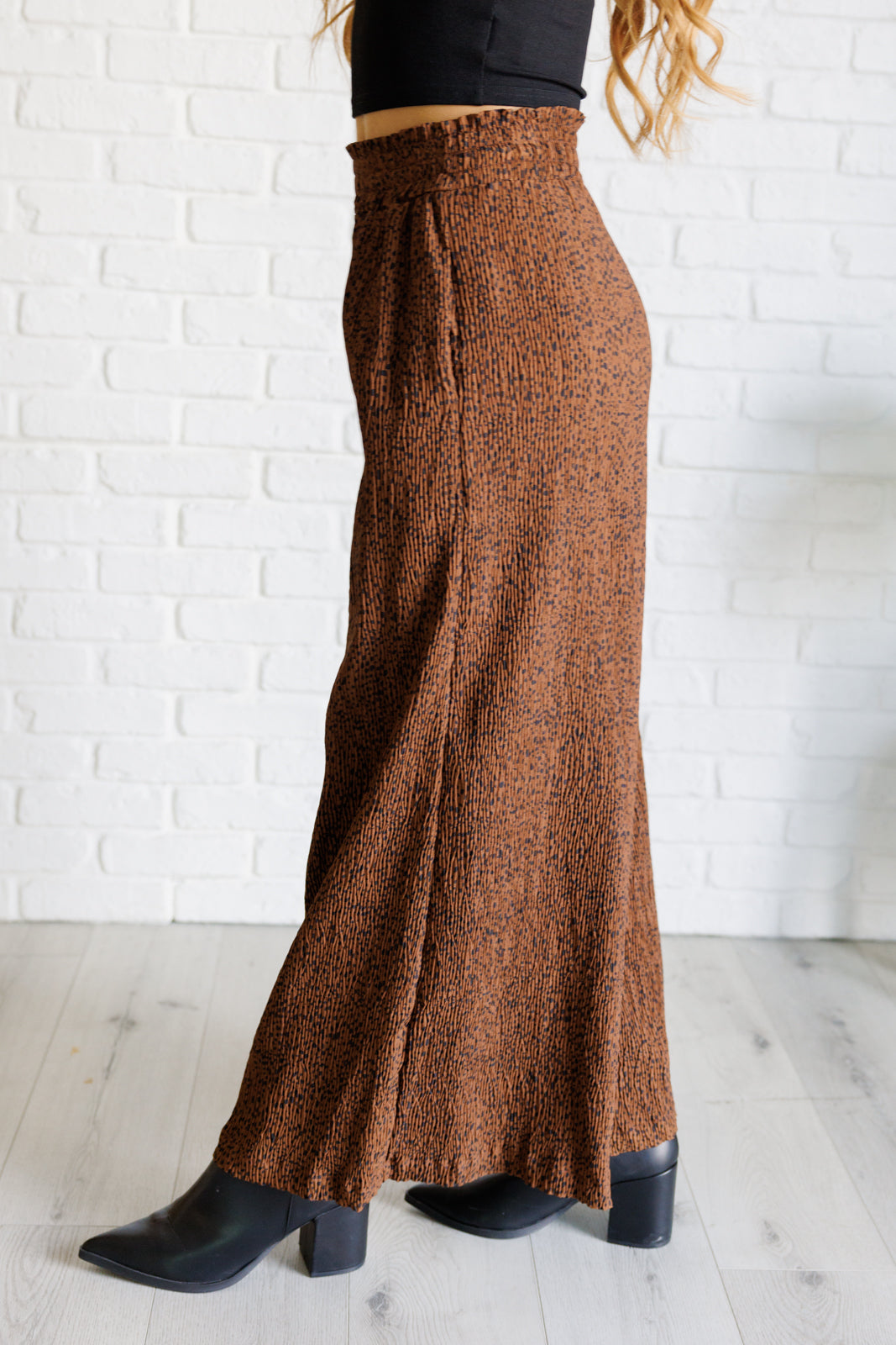 High-rise wide-leg pants in brown with a polka dot print, smocked elastic waistband, textured fabric, and pockets.