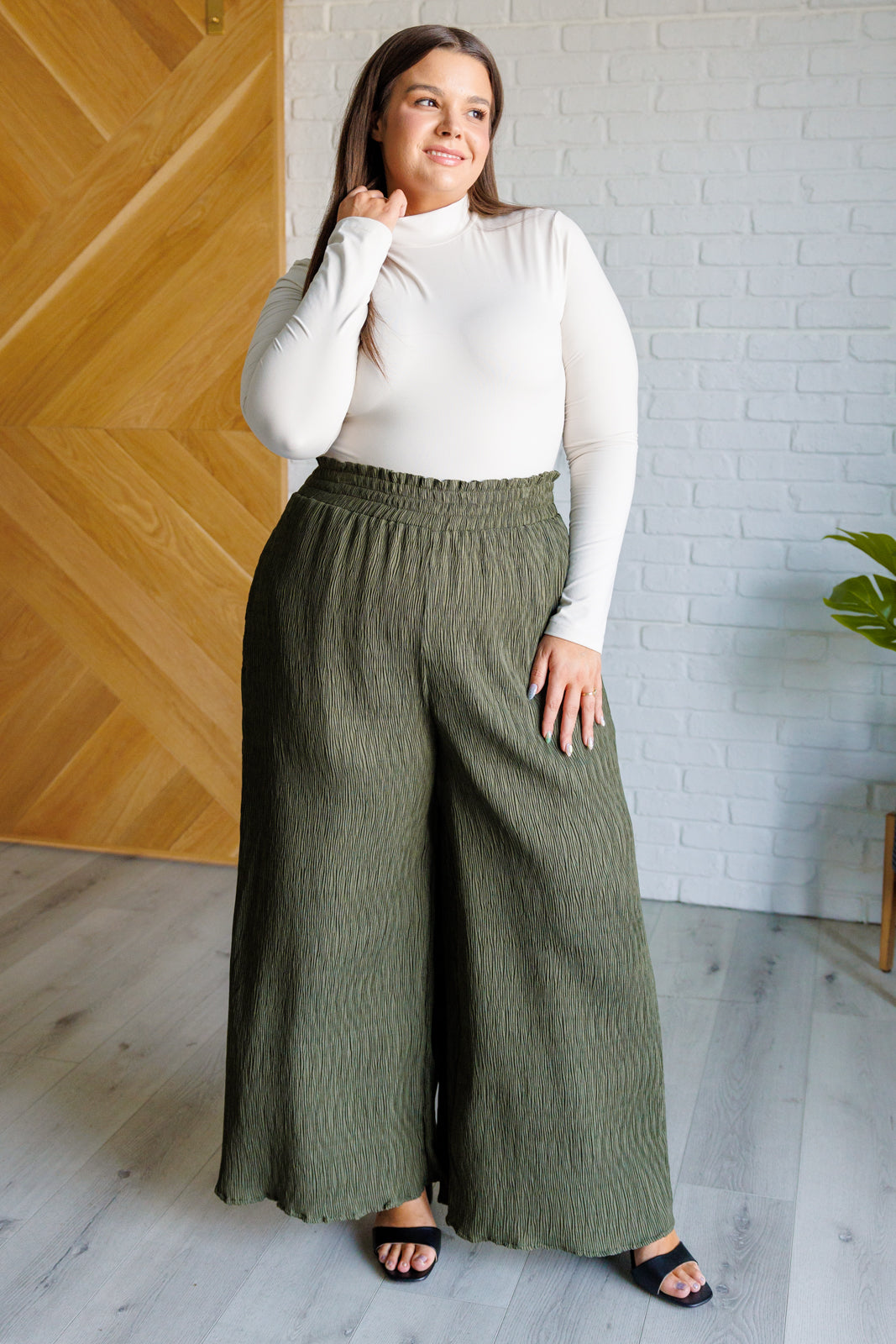 High Rise Wide Leg Pants in olive with a smocked elastic waistband, textured crinkle woven fabric, and subtle polka dot print. Featuring a wide-leg silhouette and functional pockets for a chic, standout look.