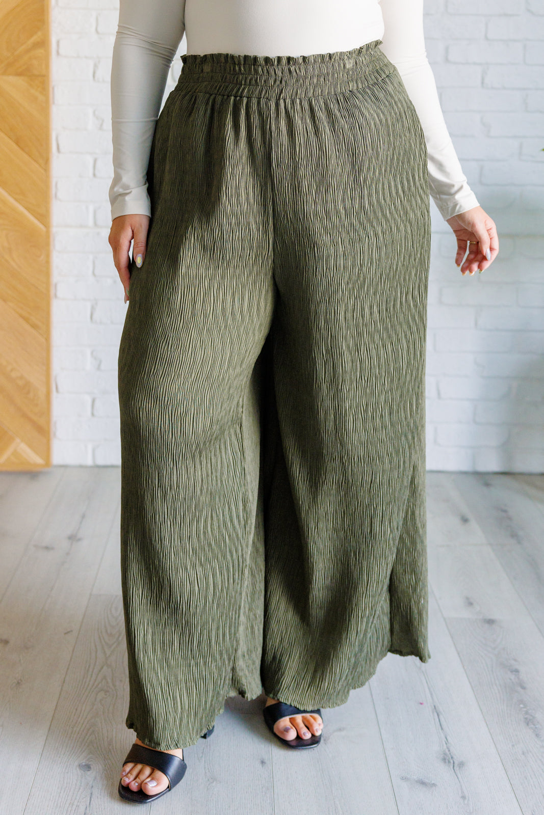 High Rise Wide Leg Pants in olive with a smocked elastic waistband, textured crinkle woven fabric, and subtle polka dot print. Featuring a wide-leg silhouette and functional pockets for a chic, standout look.