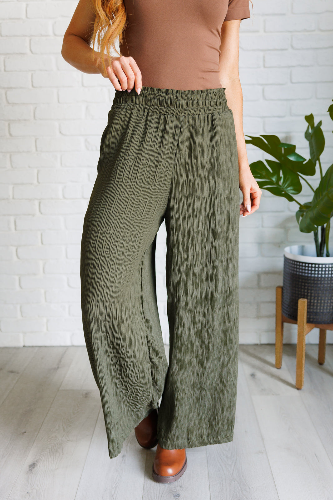 High Rise Wide Leg Pants in olive with a smocked elastic waistband, textured crinkle woven fabric, and subtle polka dot print. Featuring a wide-leg silhouette and functional pockets for a chic, standout look.