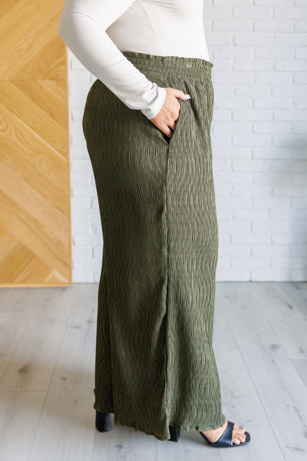 High Rise Wide Leg Pants in olive with a smocked elastic waistband, textured crinkle woven fabric, and subtle polka dot print. Featuring a wide-leg silhouette and functional pockets for a chic, standout look.