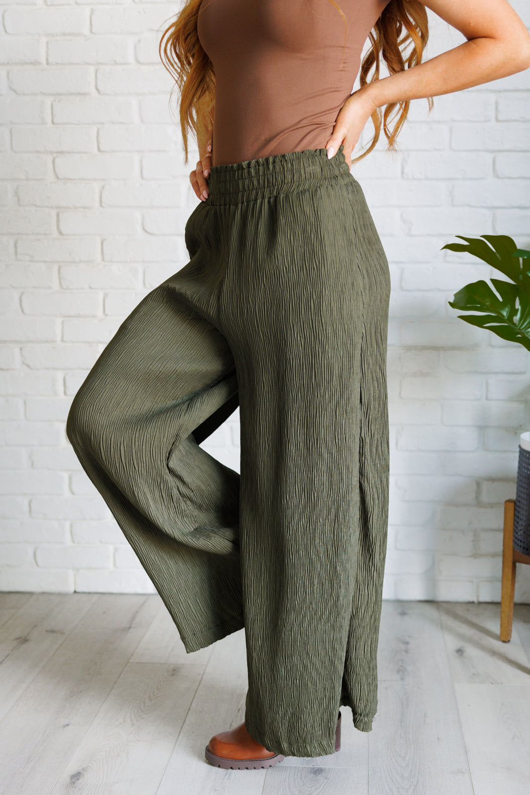 High Rise Wide Leg Pants in olive with a smocked elastic waistband, textured crinkle woven fabric, and subtle polka dot print. Featuring a wide-leg silhouette and functional pockets for a chic, standout look.