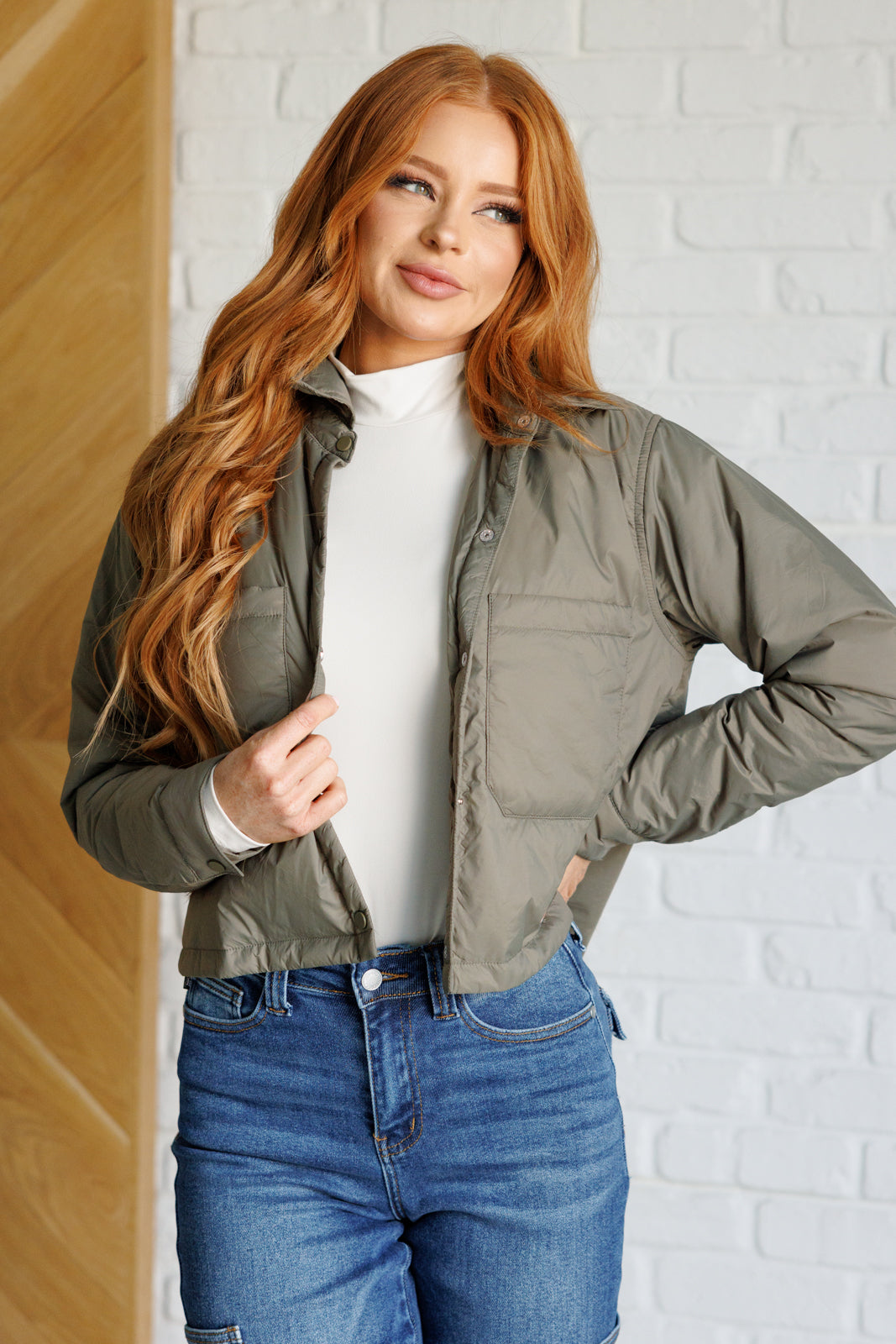 Olive lightweight puffer jacket with a collared neckline, long sleeves, snap front closure, cropped length, patch pockets, and a boxy silhouette.