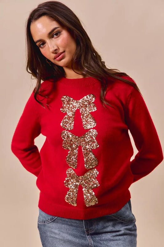 Model wearing Hermione Christmas Sweater in red with gold sequin bow embellishment.