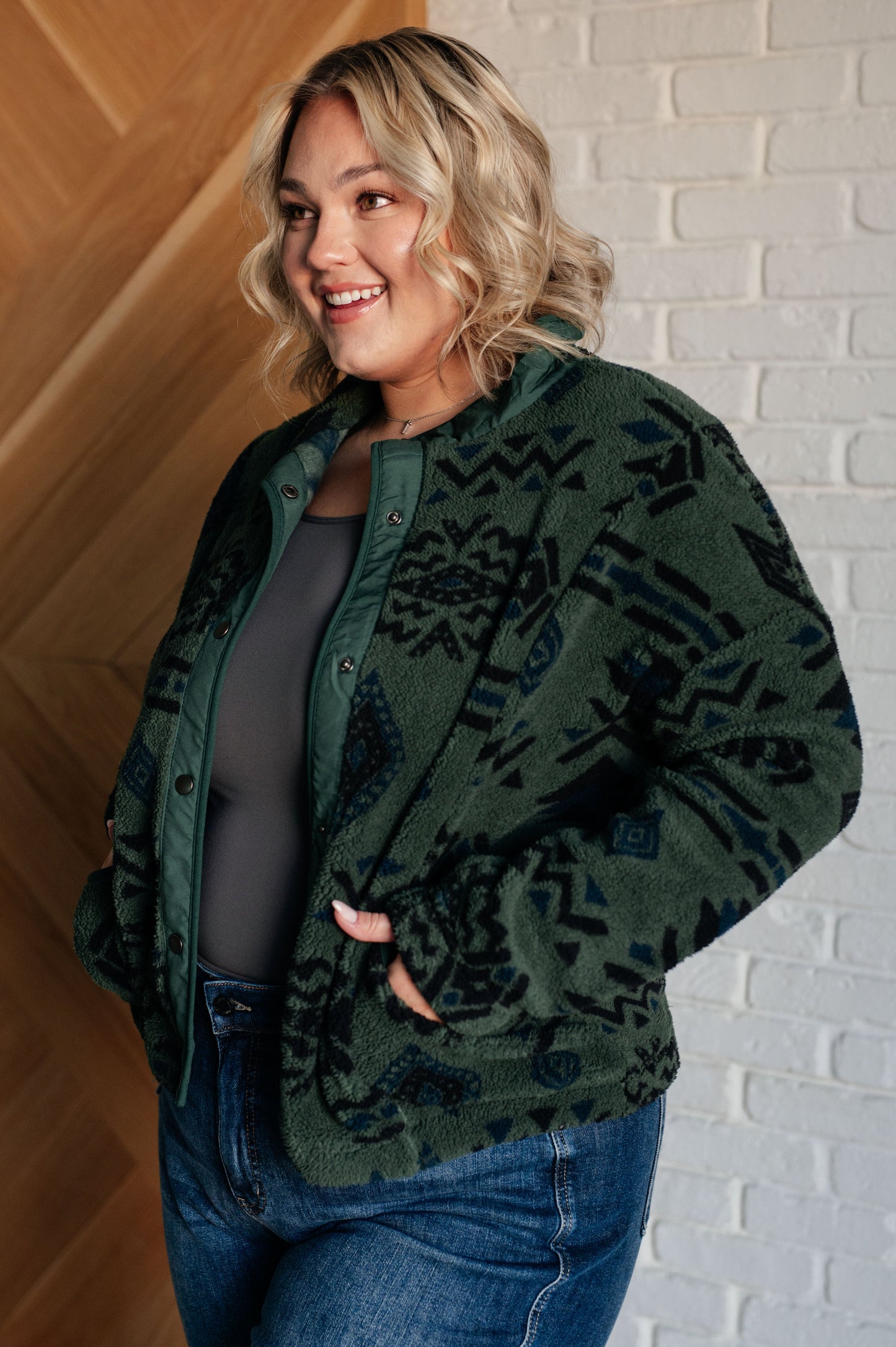 Women's green jacket made of soft polar fleece with a geometric pattern, featuring a snap front, mock neckline, front pockets, contoured seams, and dropped shoulders.