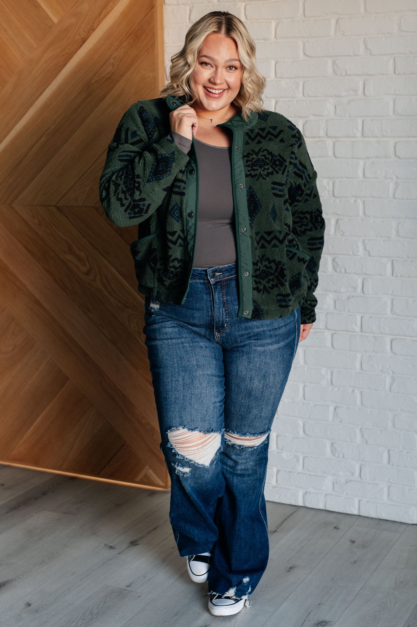 Women's green jacket made of soft polar fleece with a geometric pattern, featuring a snap front, mock neckline, front pockets, contoured seams, and dropped shoulders.