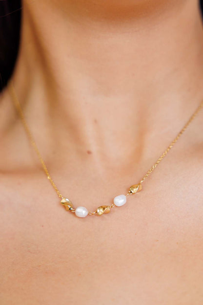 Close-up of model wearing pearl necklace with 18K gold twisted charms