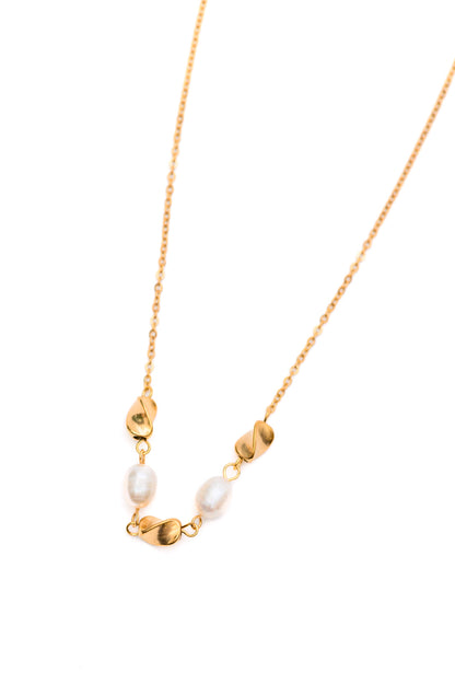 Flat lay of pearl necklace with gold charms on white background