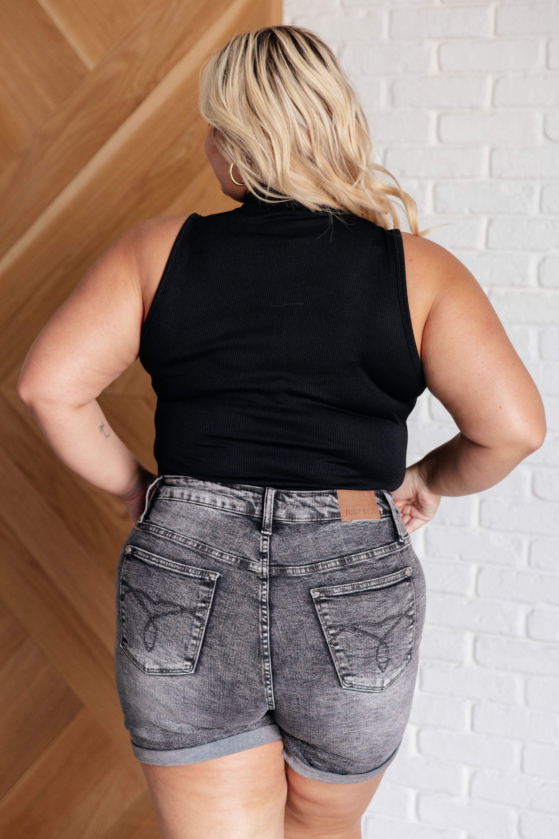 Back view of plus size woman wearing the Marley Ribbed Zip Up Bodysuit in black, showcasing the ribbed knit fabric.