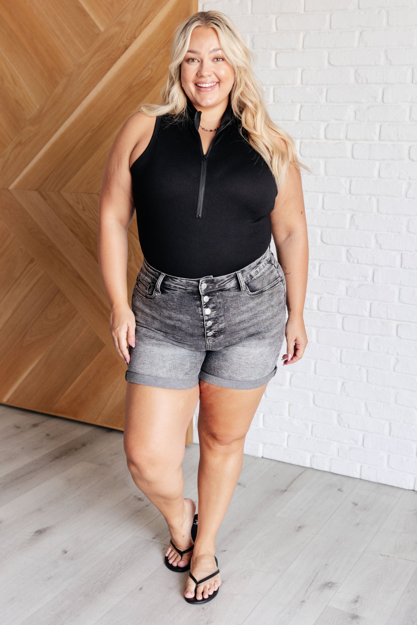 Front view of plus size Marley Ribbed Zip Up Bodysuit in black, showing mock neckline, half zip closure, and ribbed knit fabric.